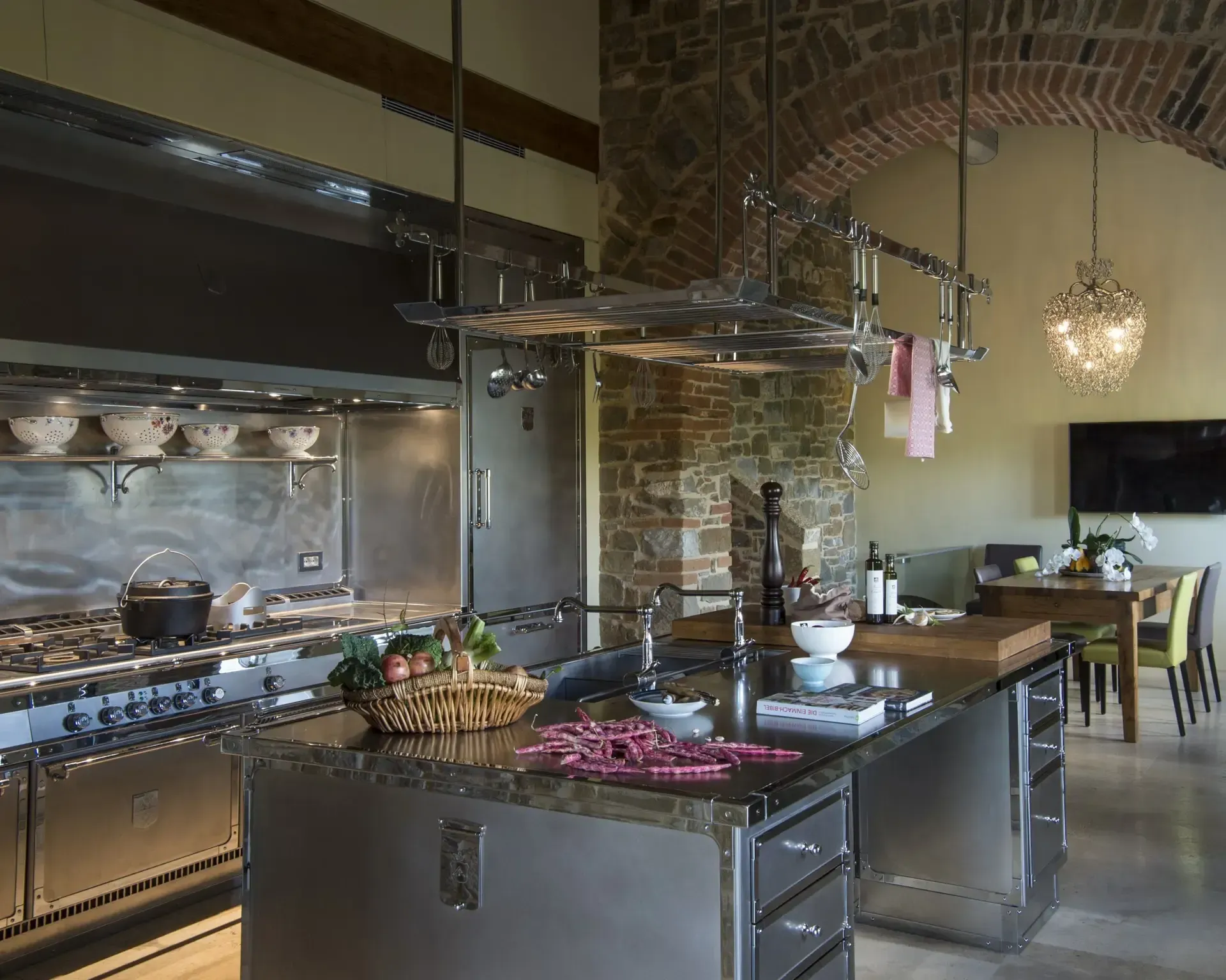 Stainless steel kitchen with large island, stove, and stone archway.