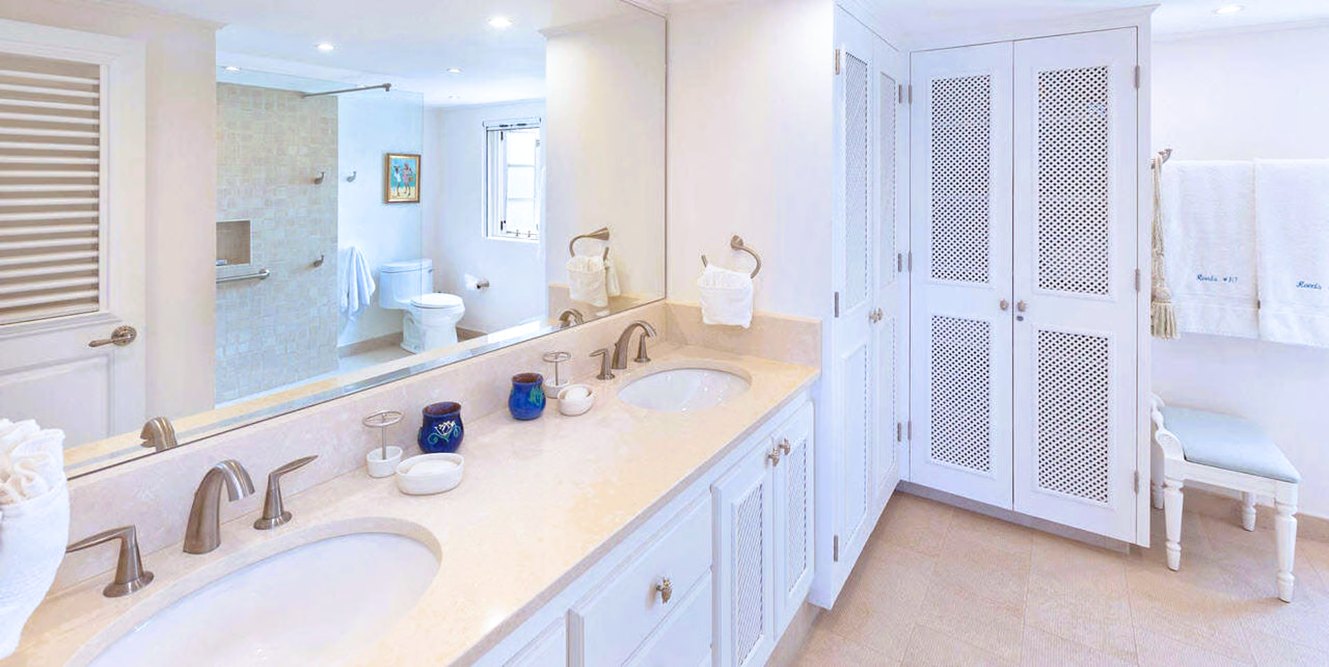 Bathroom with double vanity, mirror, white cabinets, and shower.
