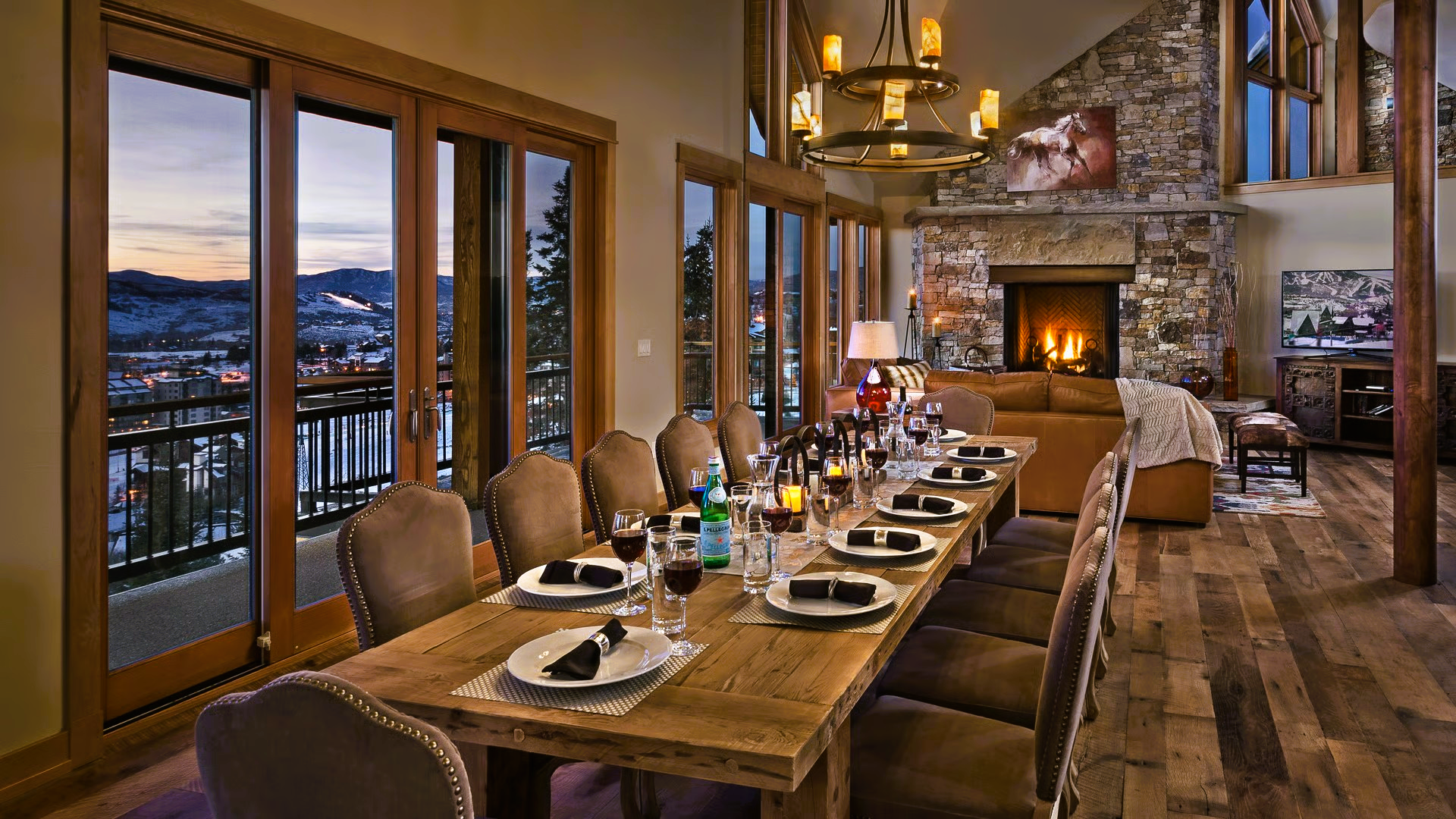 Dining room with long wooden table, place settings, fireplace, and mountain view.