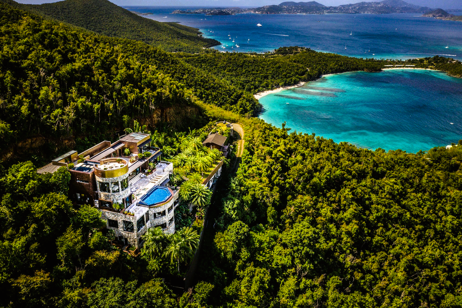 Luxurious, abandoned villa amidst lush green tropical forest overlooking turquoise ocean and coastline.