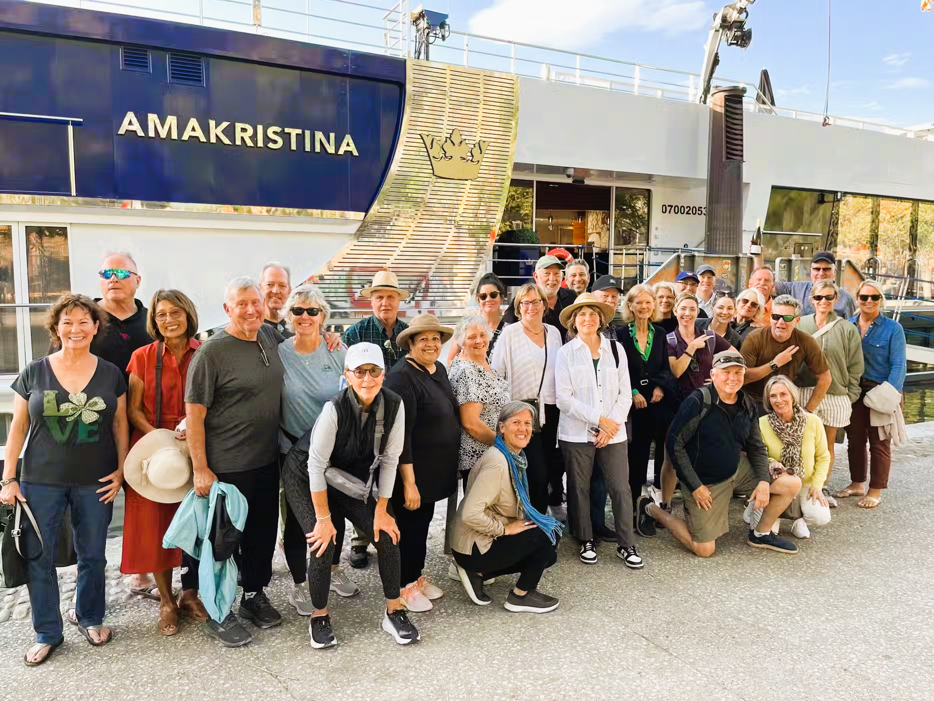 A large group of people are posing for a picture in front of a boat.