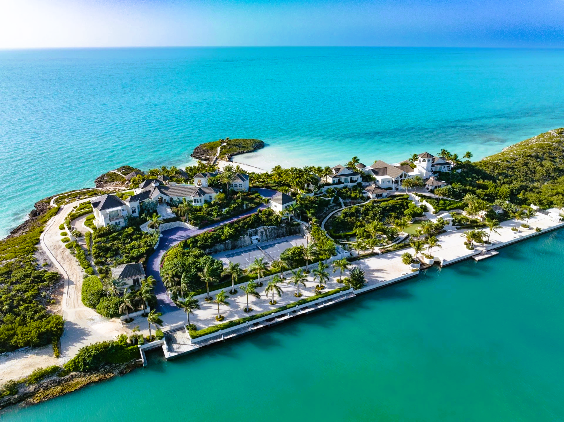 Luxury homes on a peninsula with turquoise water and lush greenery.