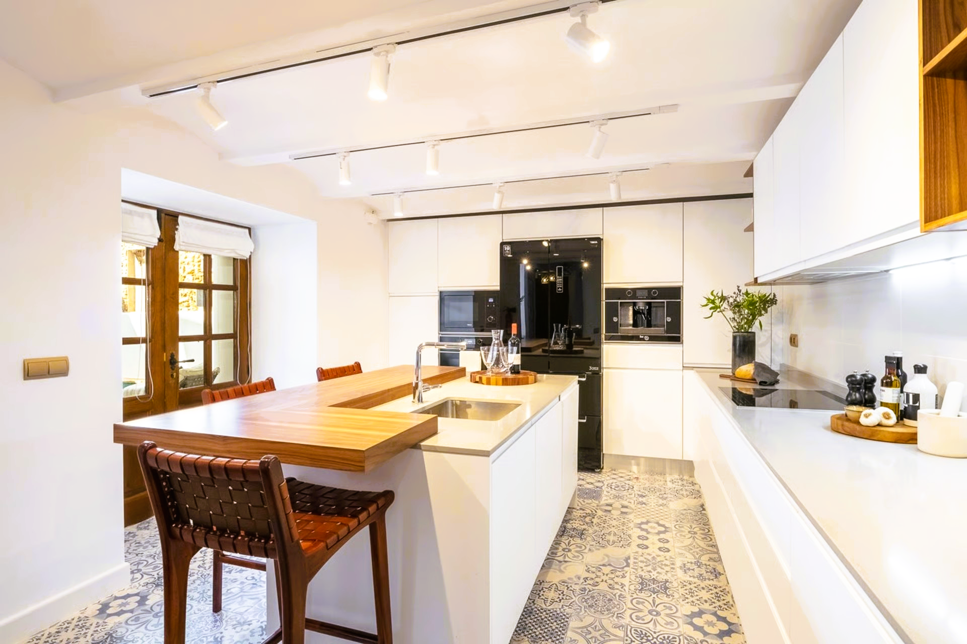 Modern white kitchen with wood accents, island, and a breakfast bar.