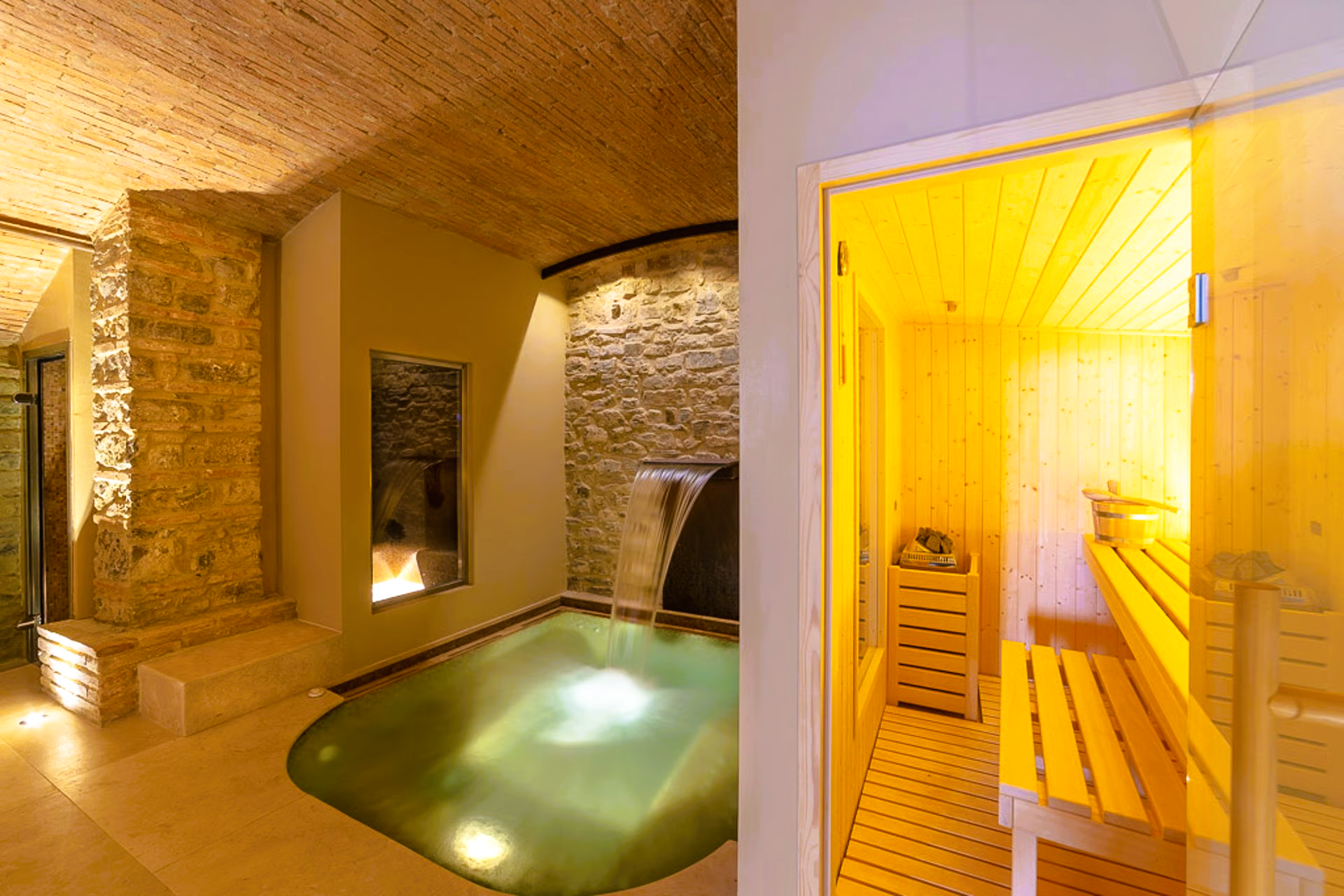 Spa area with pool, sauna, stone walls, and warm lighting.