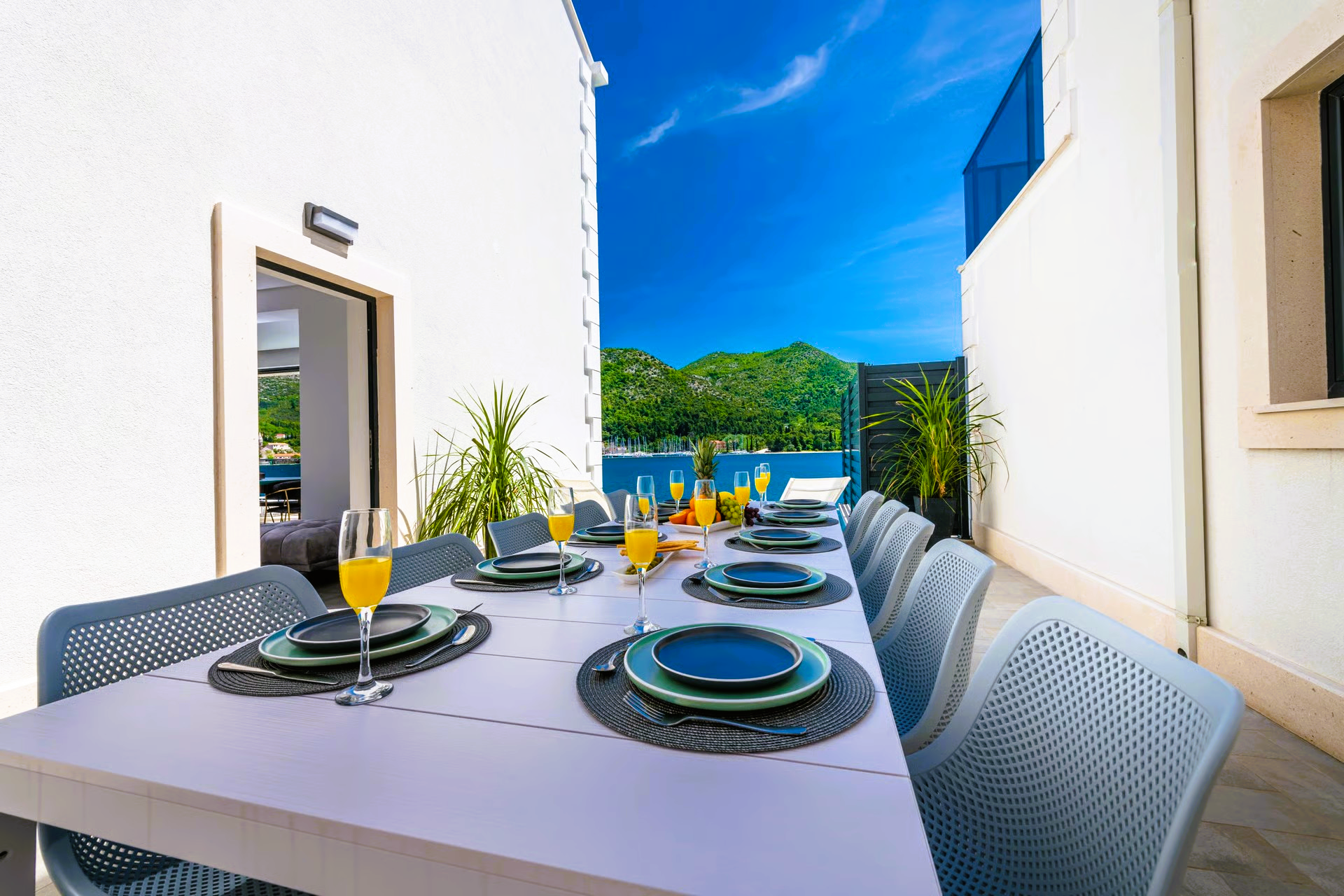 Outdoor dining table set for a meal, with blue water and sky in the background.