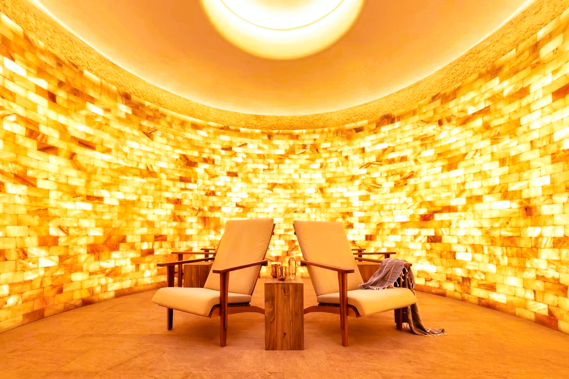 Two chairs in a salt room, illuminated by warm light. The walls are made of salt bricks, an inviting spa setting.