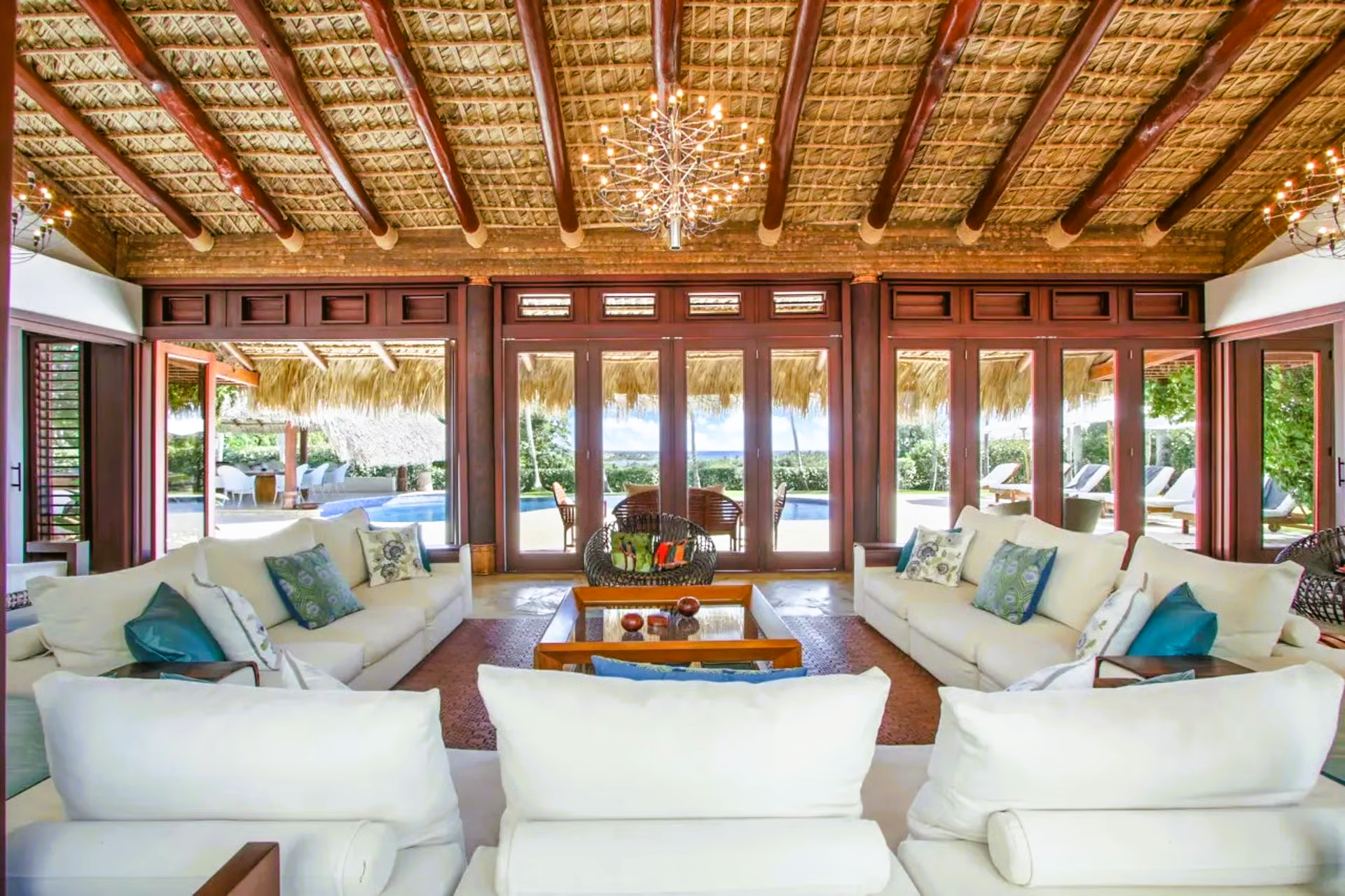 Living room with white couches, thatched roof, and ocean view.