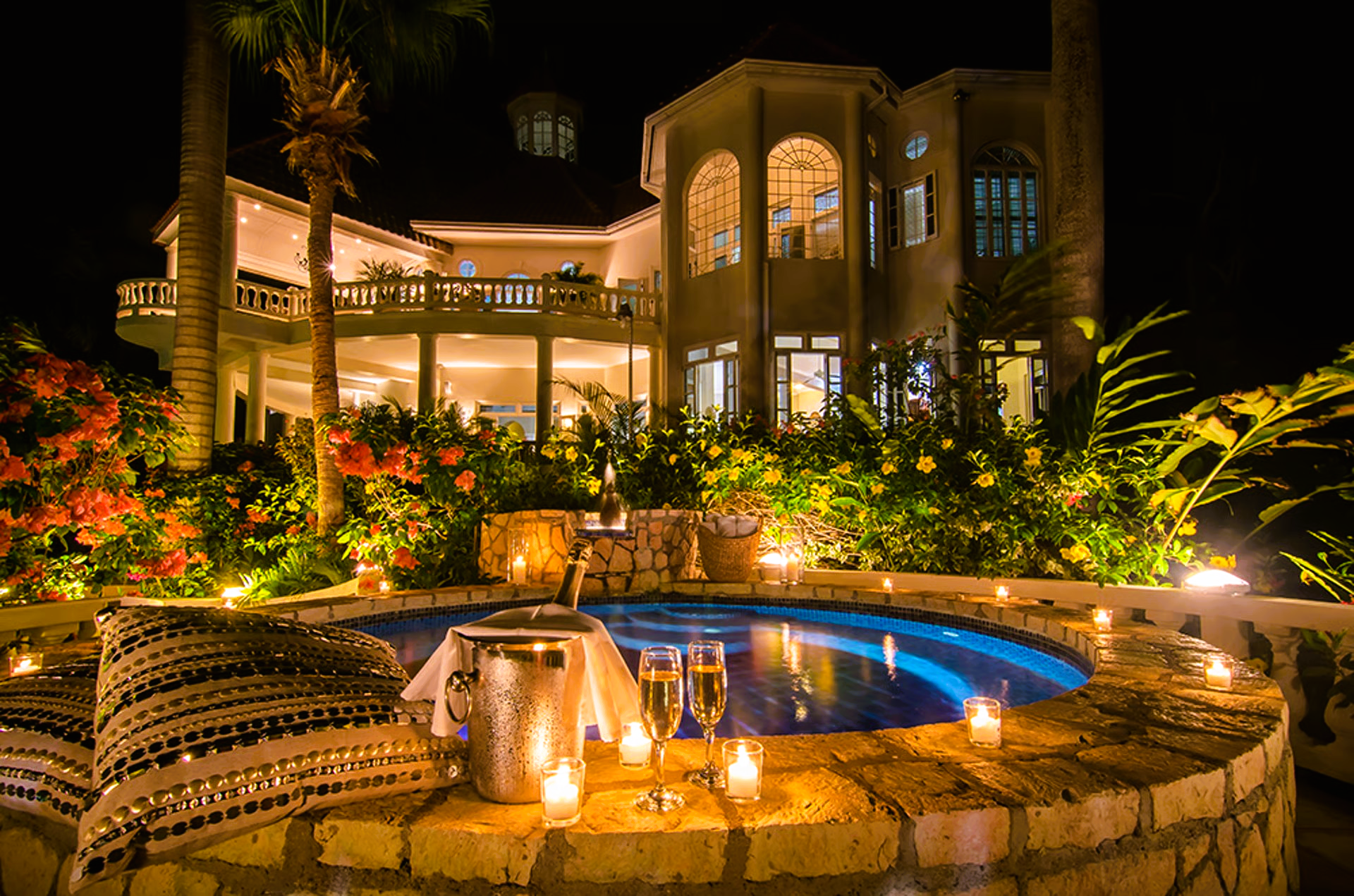 Luxury villa at night, lit hot tub with champagne, flowers, and candles.