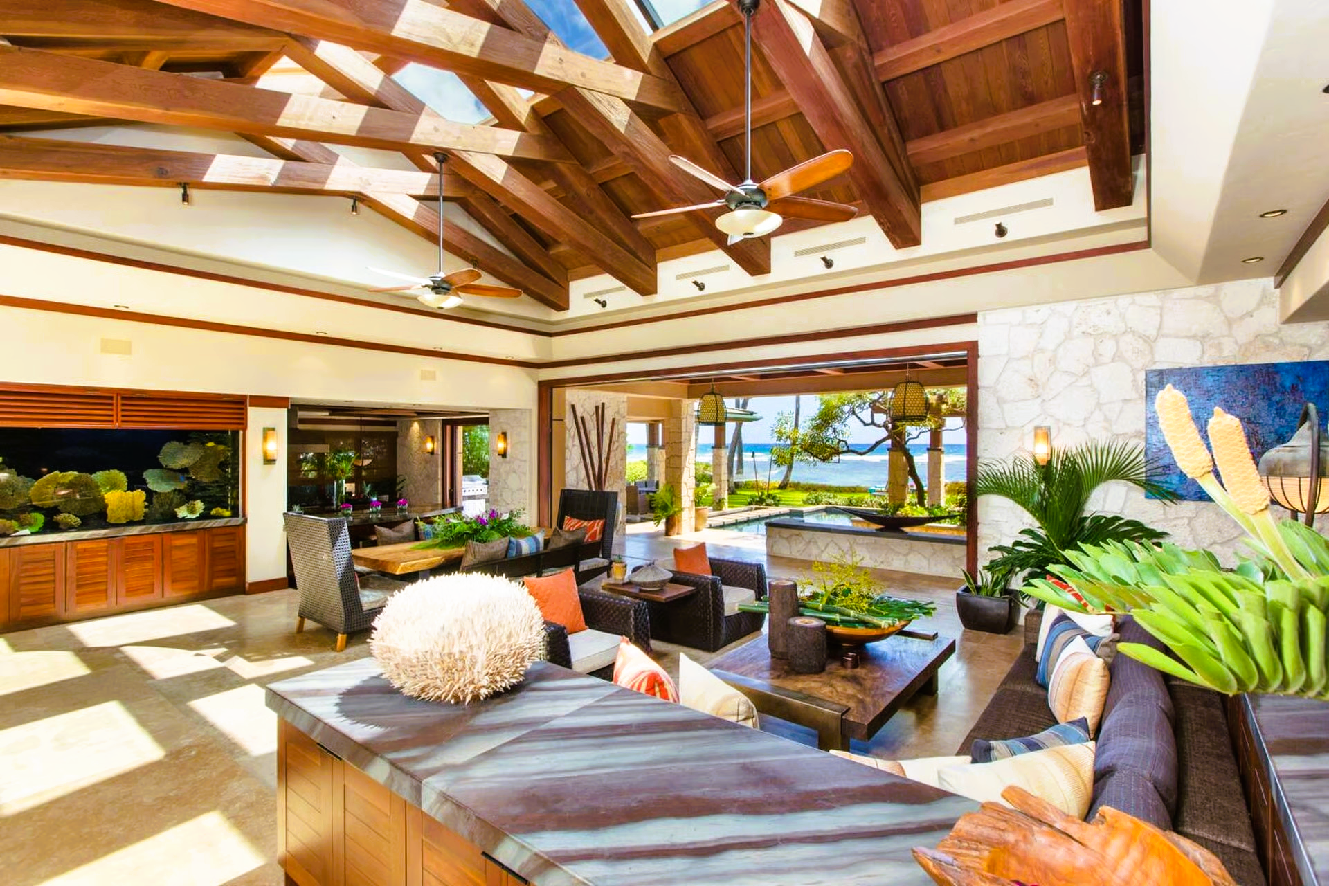 Luxurious open-concept living space with wood beams, ocean view, and stone countertops.
