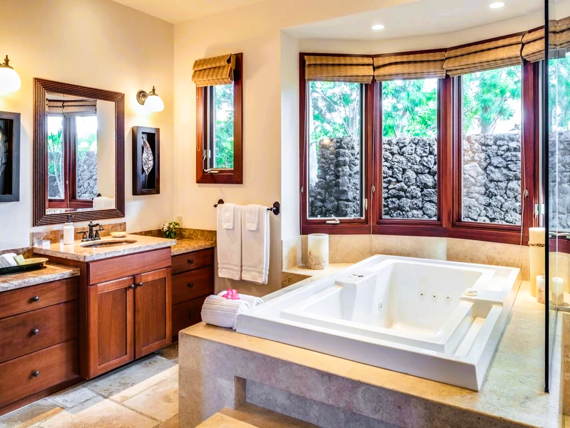 Bathroom with a built-in jacuzzi, stone walls, and wooden cabinets.
