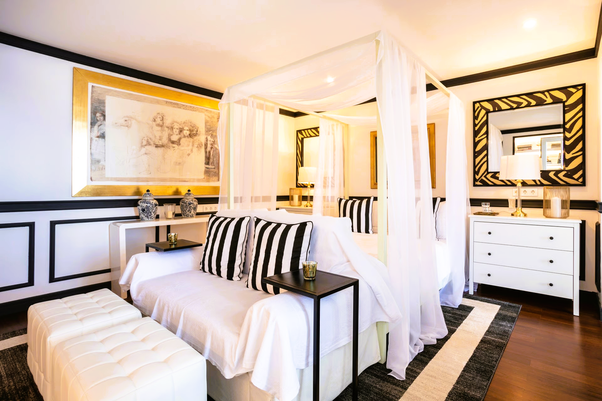 Elegant bedroom with canopy bed, black and white accents, and a sitting area.