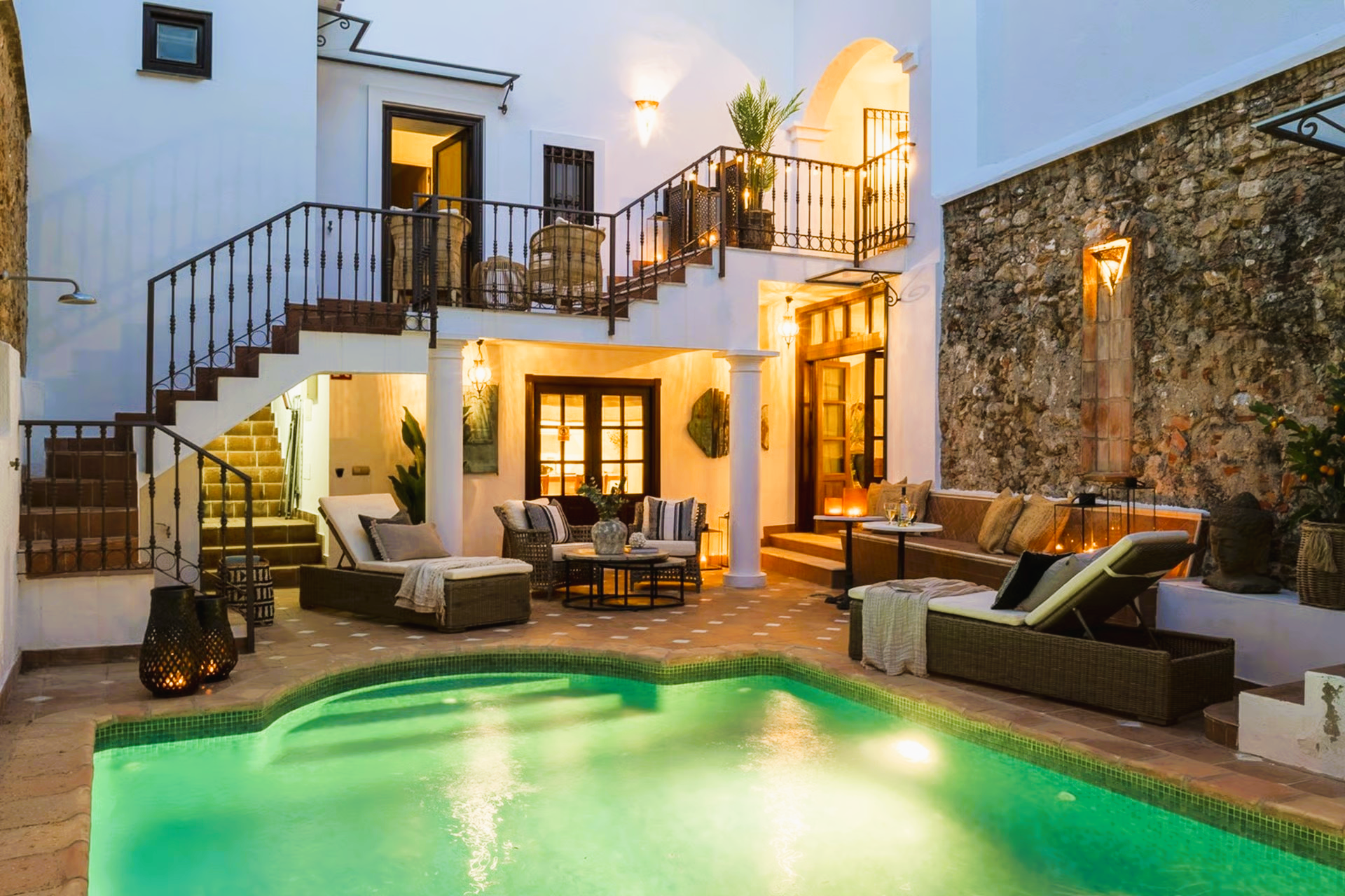 Pool and patio area with white walls, stairs, and outdoor seating.