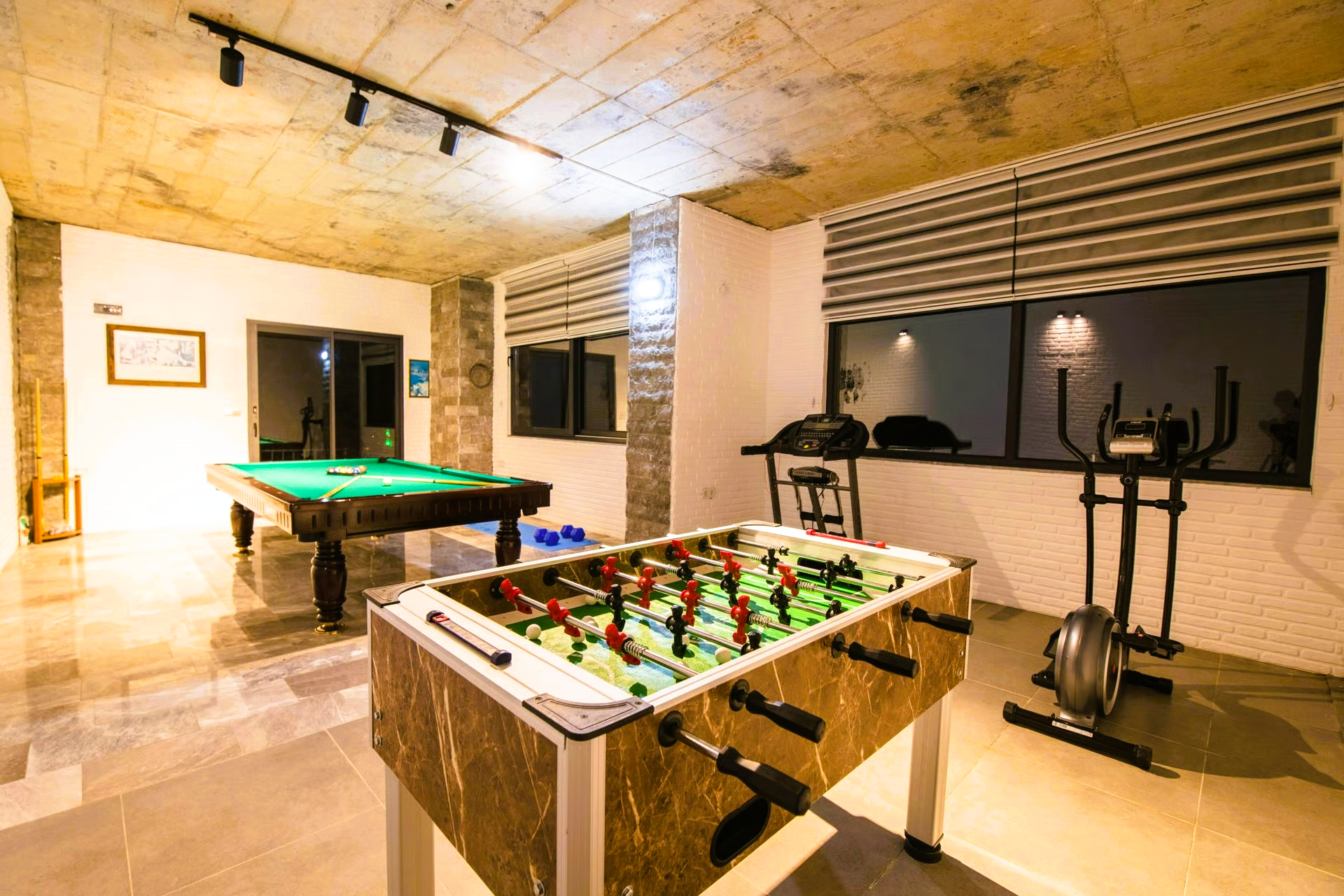 Game room with a pool table, foosball table, and elliptical machine.