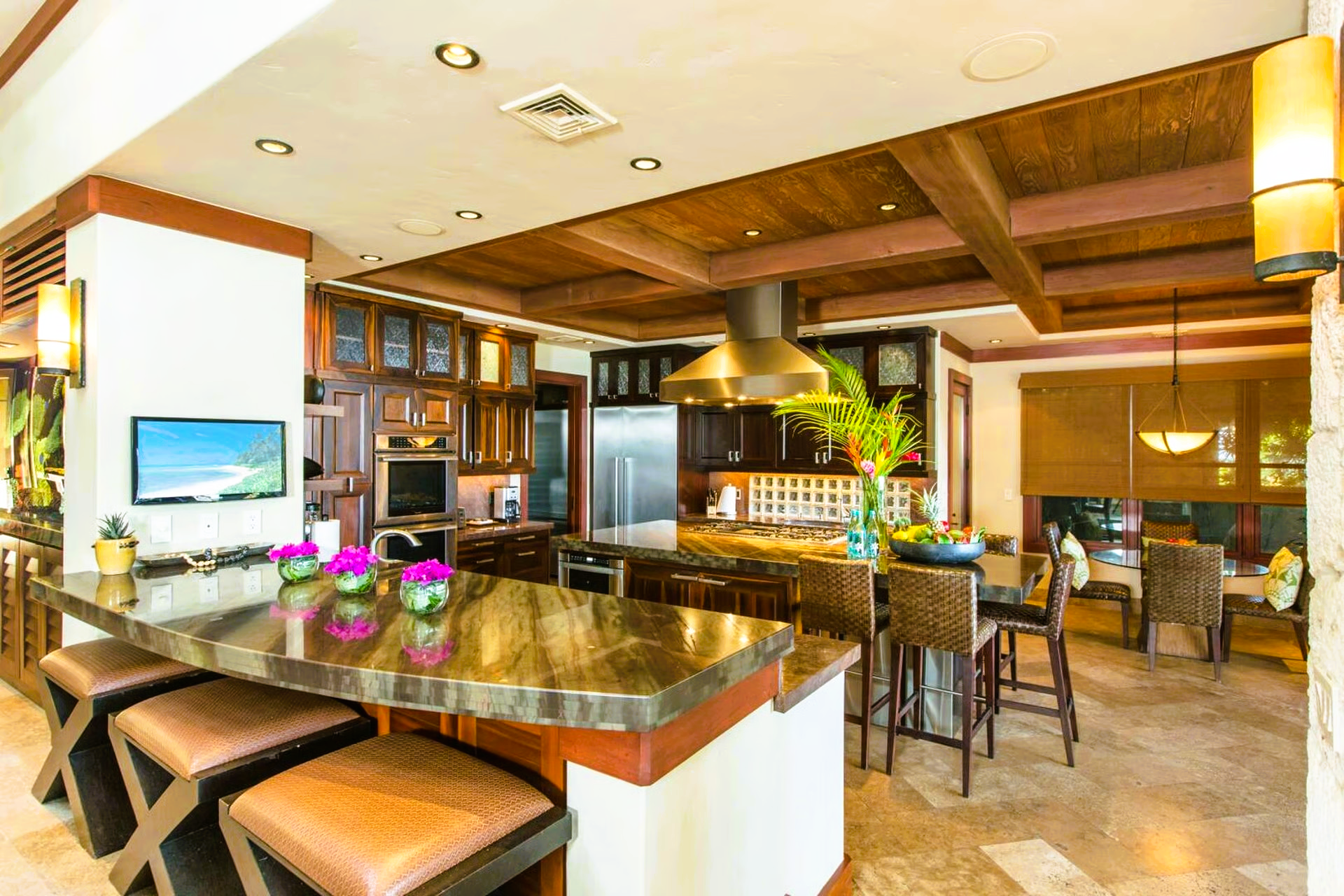 Luxurious kitchen with island, stools, wood cabinets, and dining area.