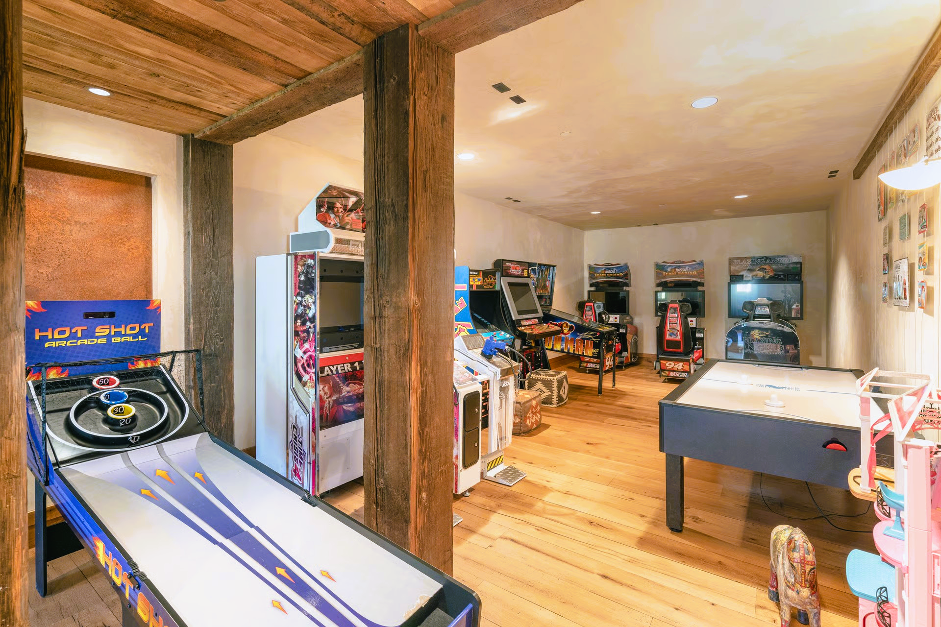 Game room with arcade games, foosball table, and wooden beams and floors.