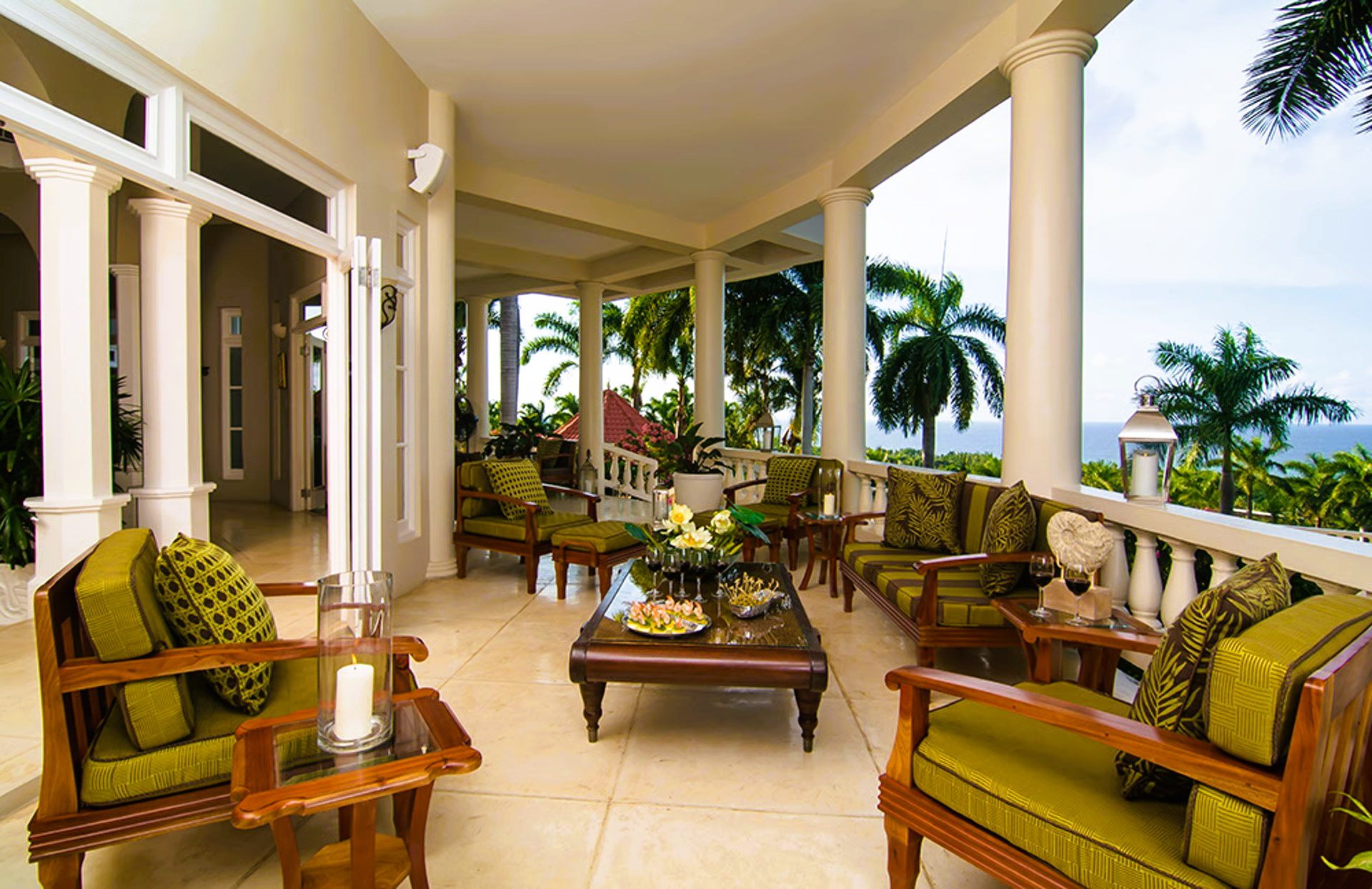Patio with green cushions, wooden furniture, and ocean view.