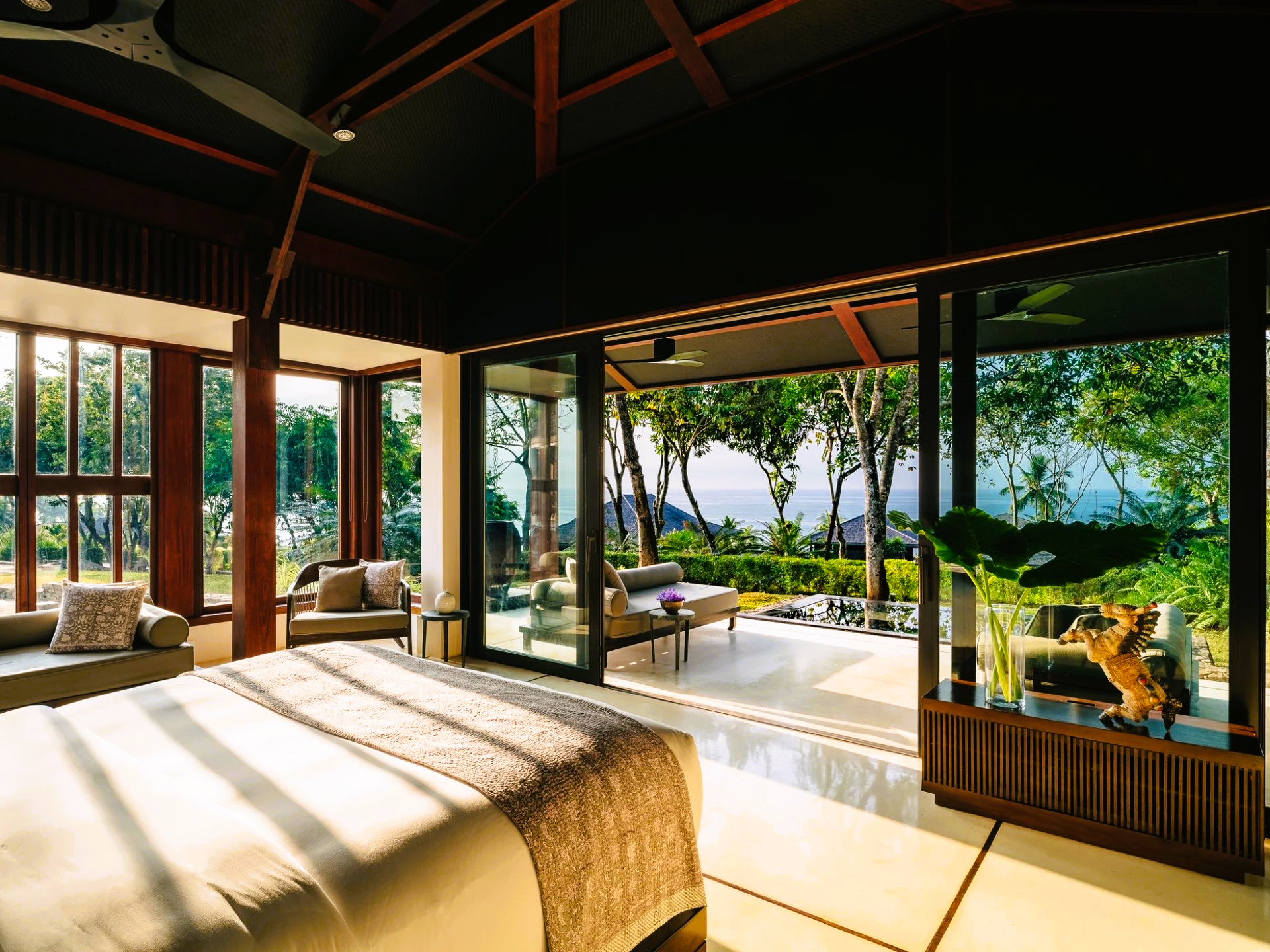 Luxurious bedroom with open doors to outdoor patio, showcasing nature views.