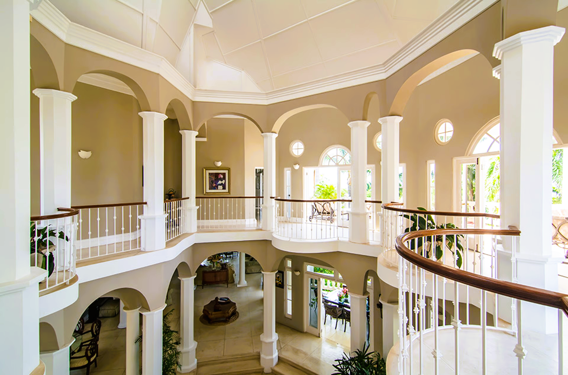 Elegant, multi-story interior with white columns, tan walls, and balconies overlooking a lower level.