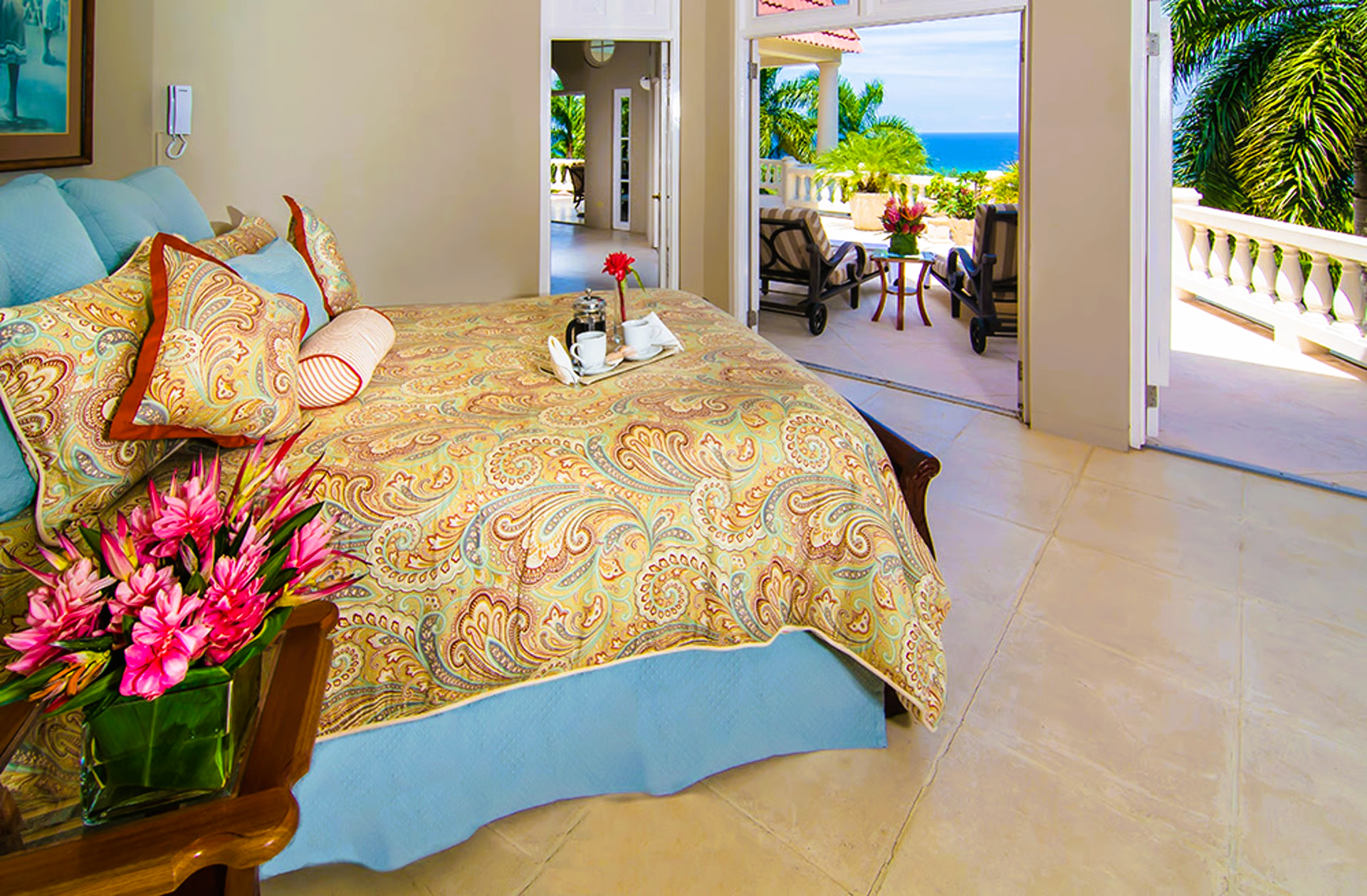 Bedroom with ornate bed, open doors to patio, ocean view.