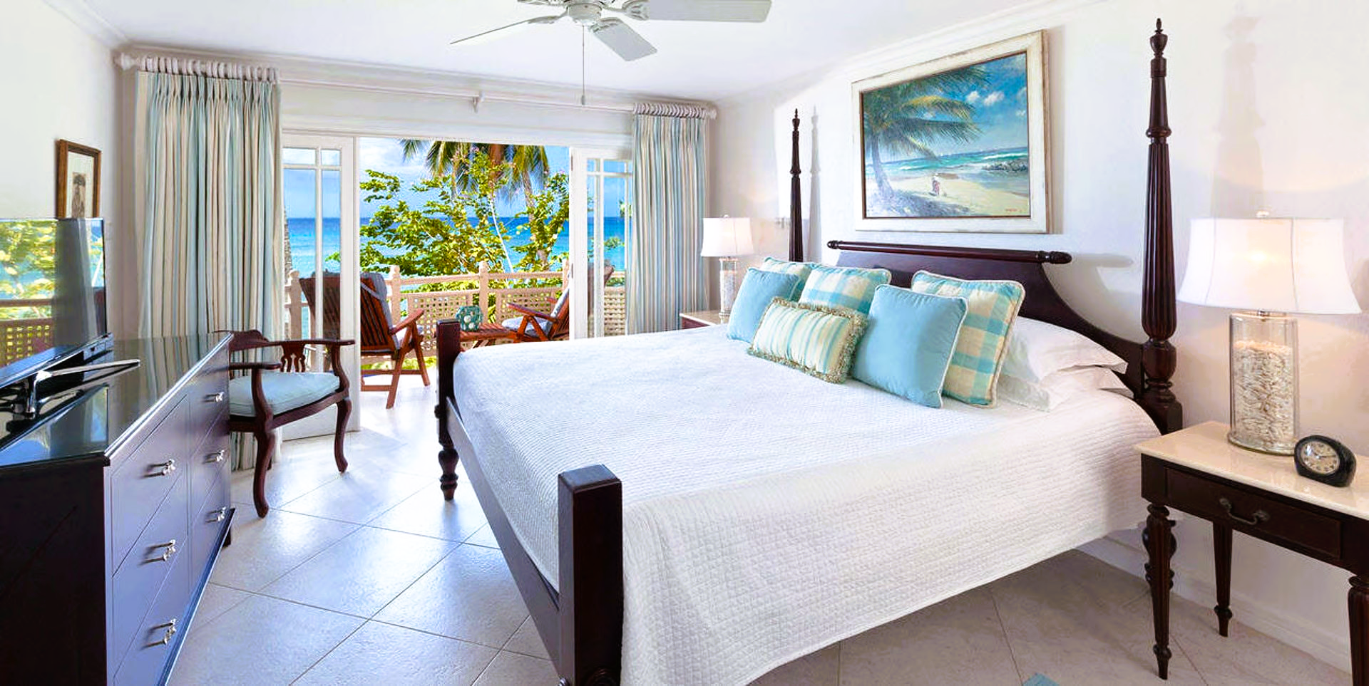 Bedroom with a bed, open balcony doors, and a view of the ocean.