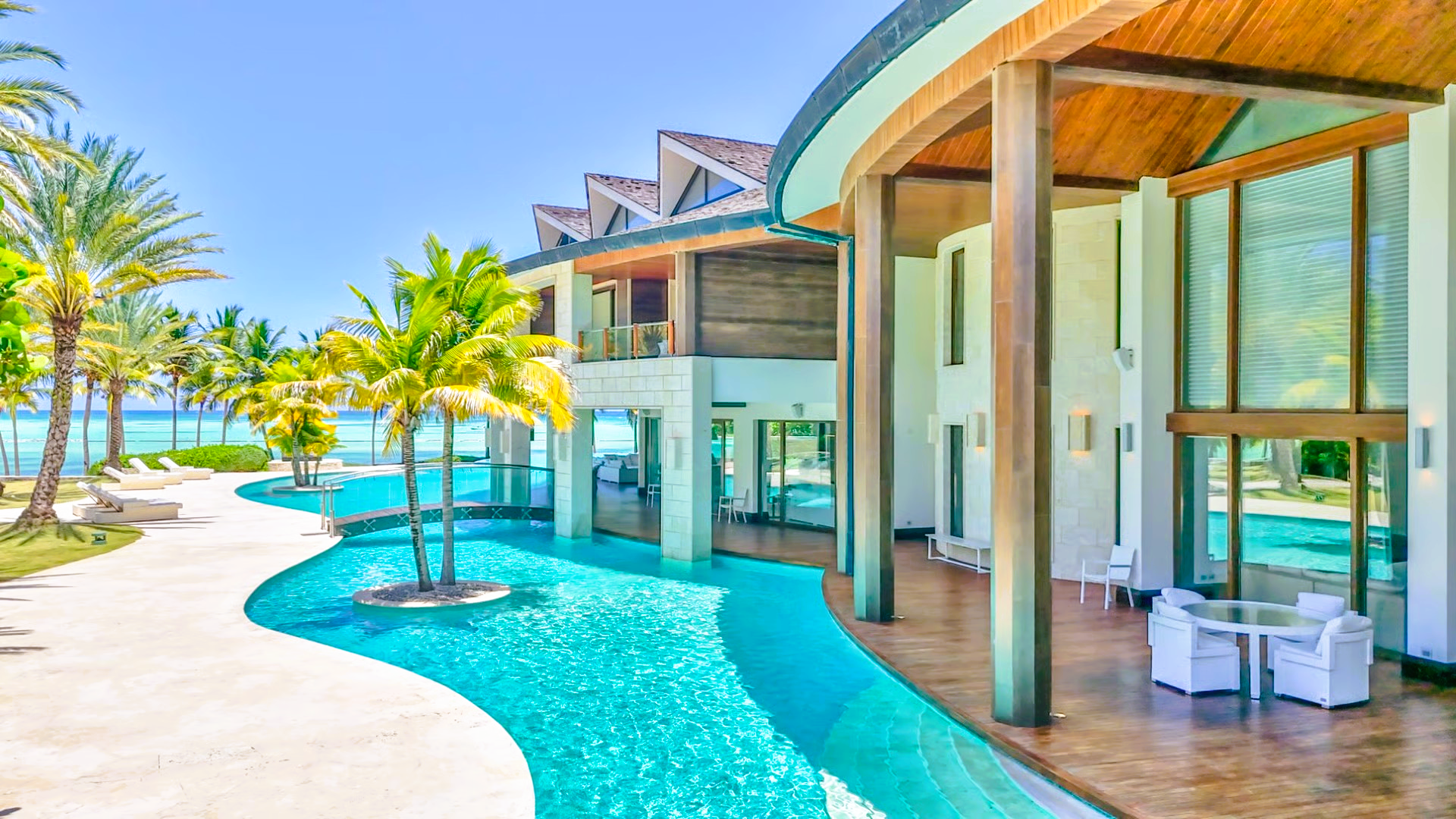 Luxury beachfront villa with pool, palm trees, and ocean view.
