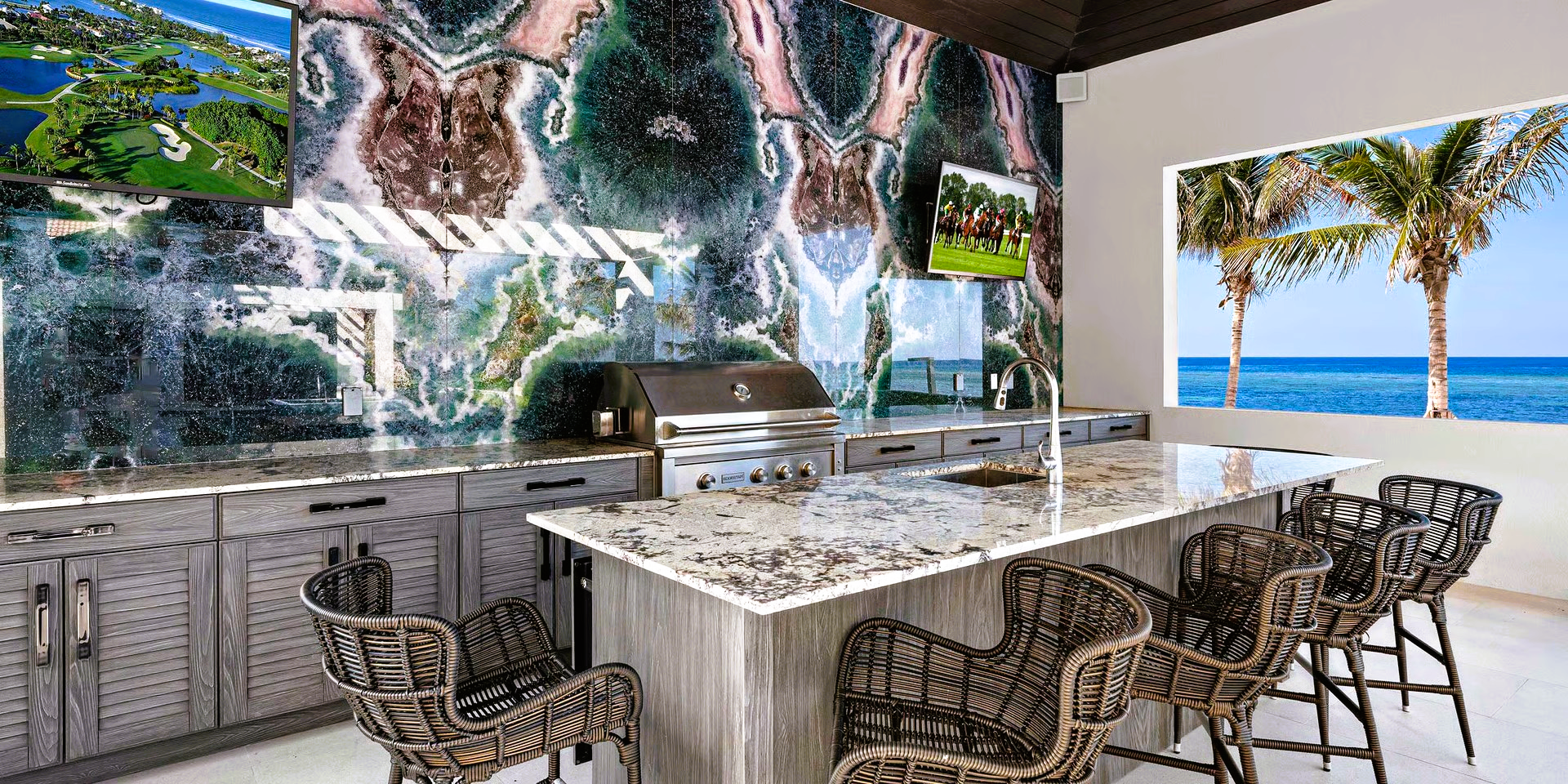 Outdoor kitchen with ocean view, stone backsplash, and bar seating.
