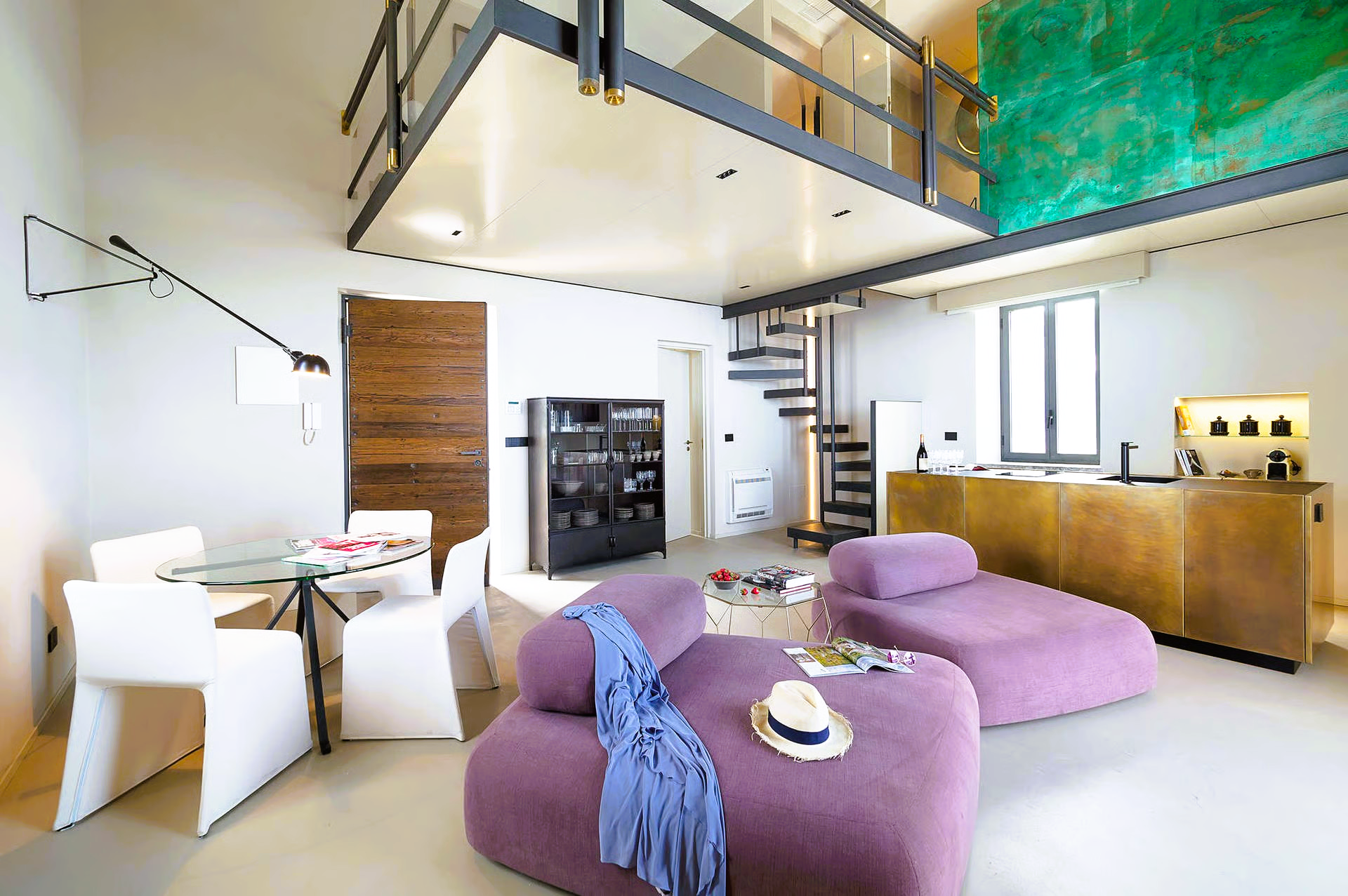 Modern, minimalist apartment with loft. Living area features purple sofas, dining set, and spiral staircase to upper level.