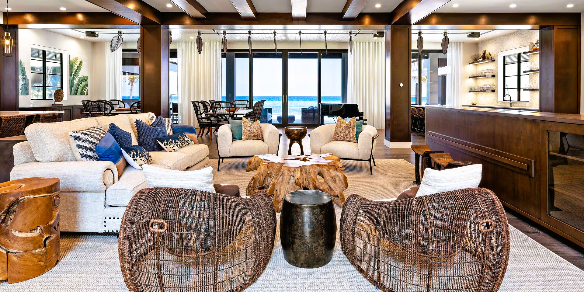 Luxurious living room with white sofas, wooden chairs, and ocean view.