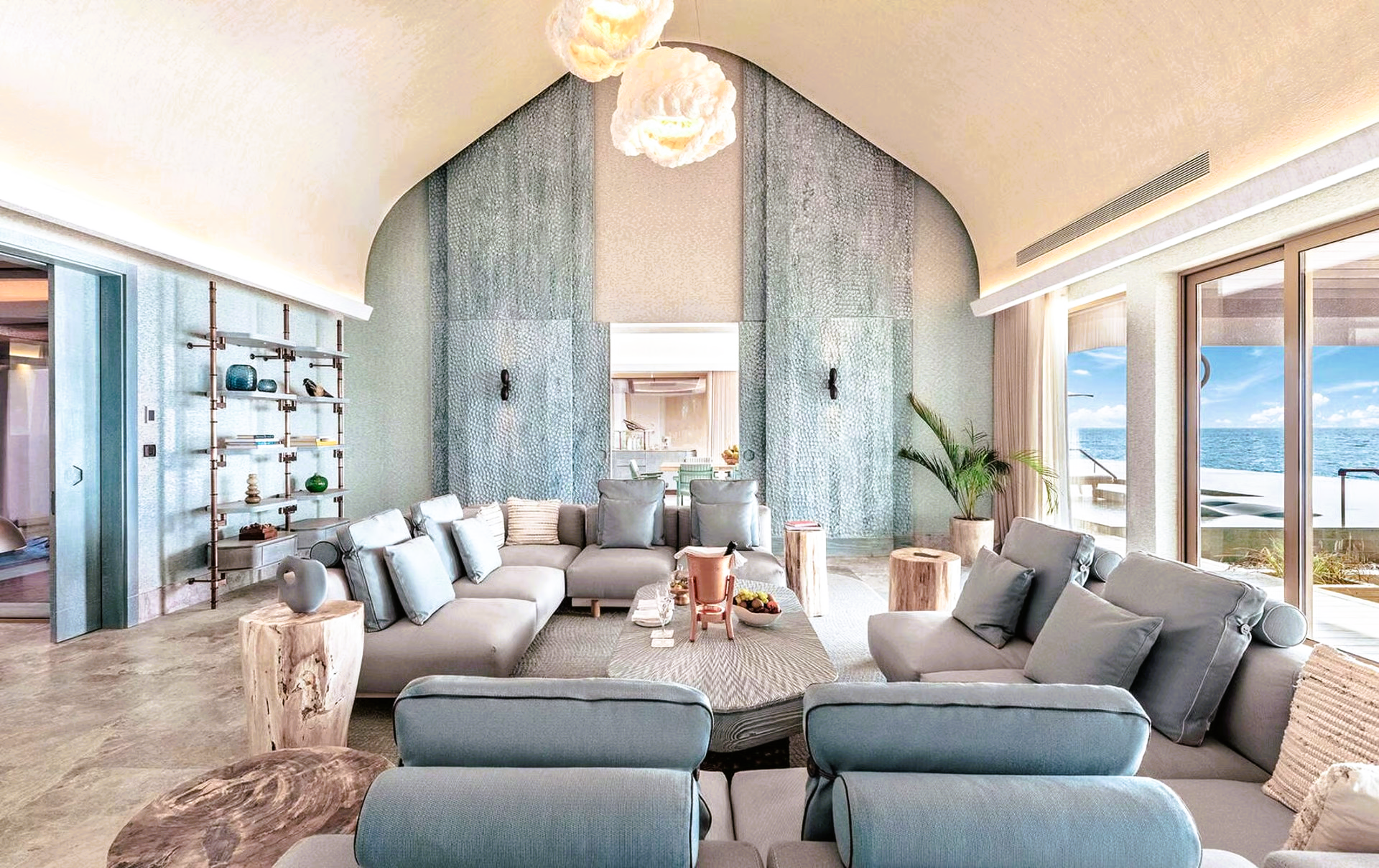 Luxurious living room with ocean view. Gray sectional sofa, light blue walls, large windows.