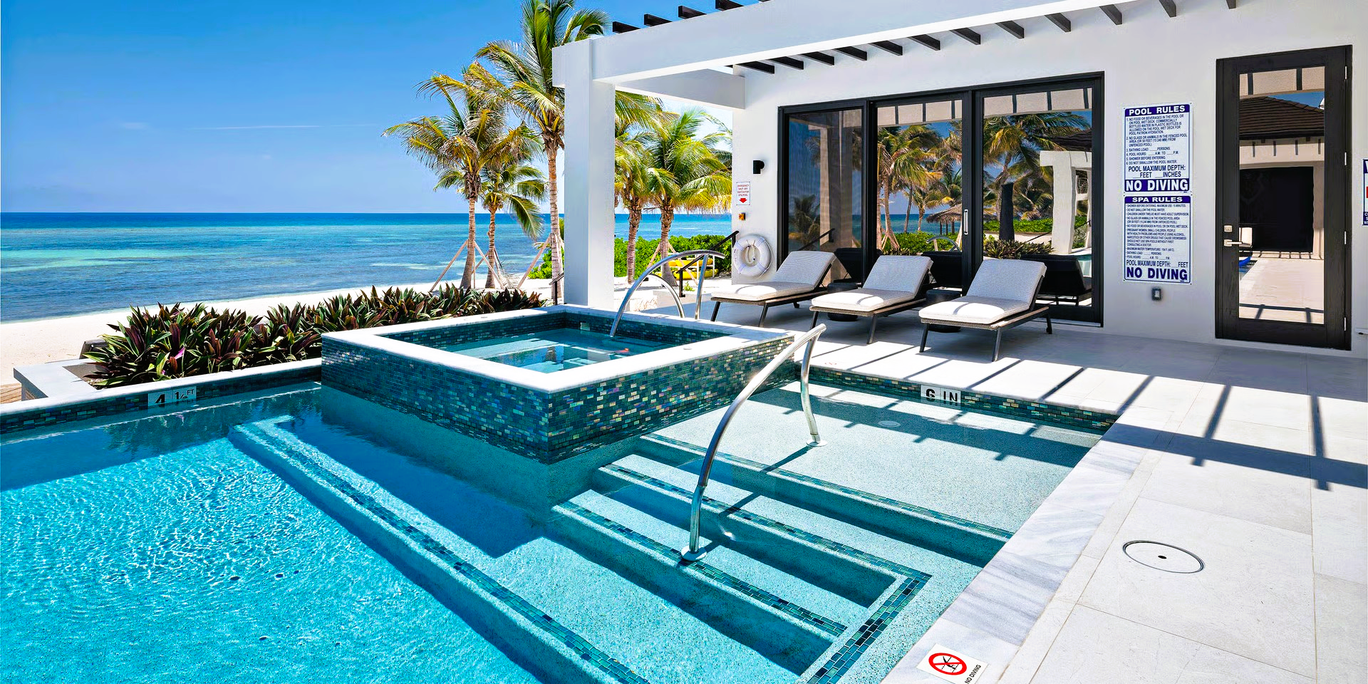 Pool and jacuzzi with ocean view, sunny day at a tropical resort.