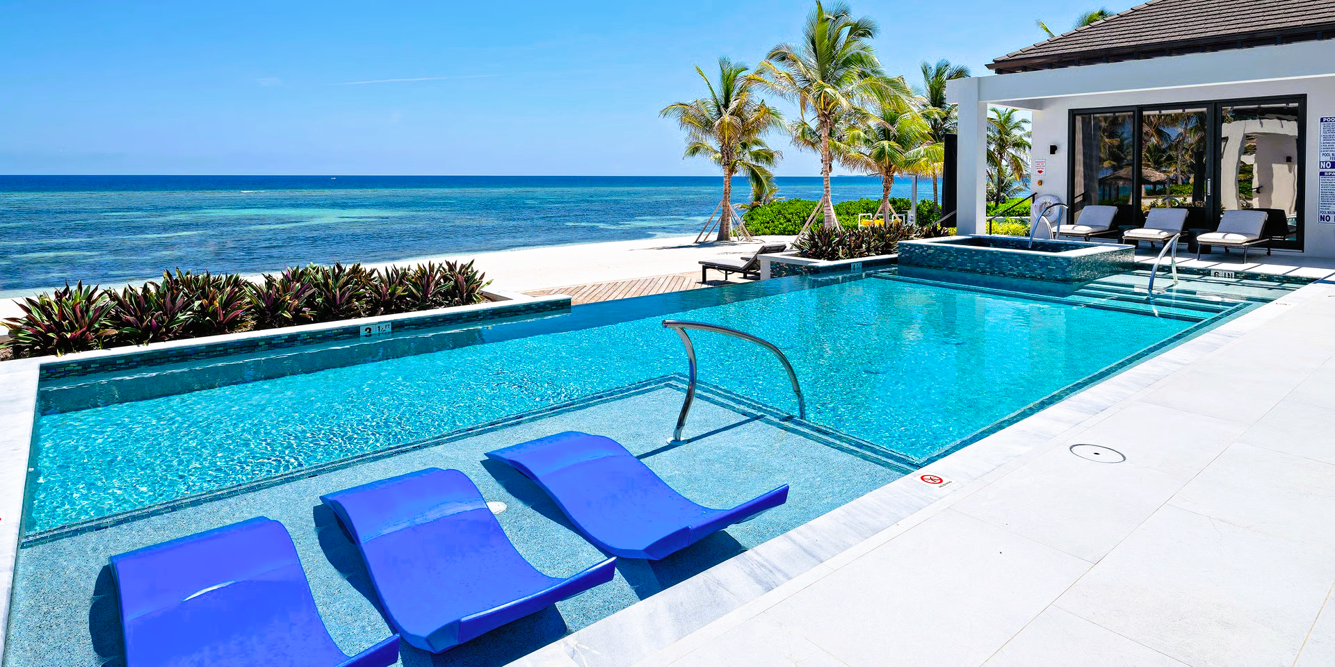 Swimming pool with blue lounge chairs overlooking the ocean.