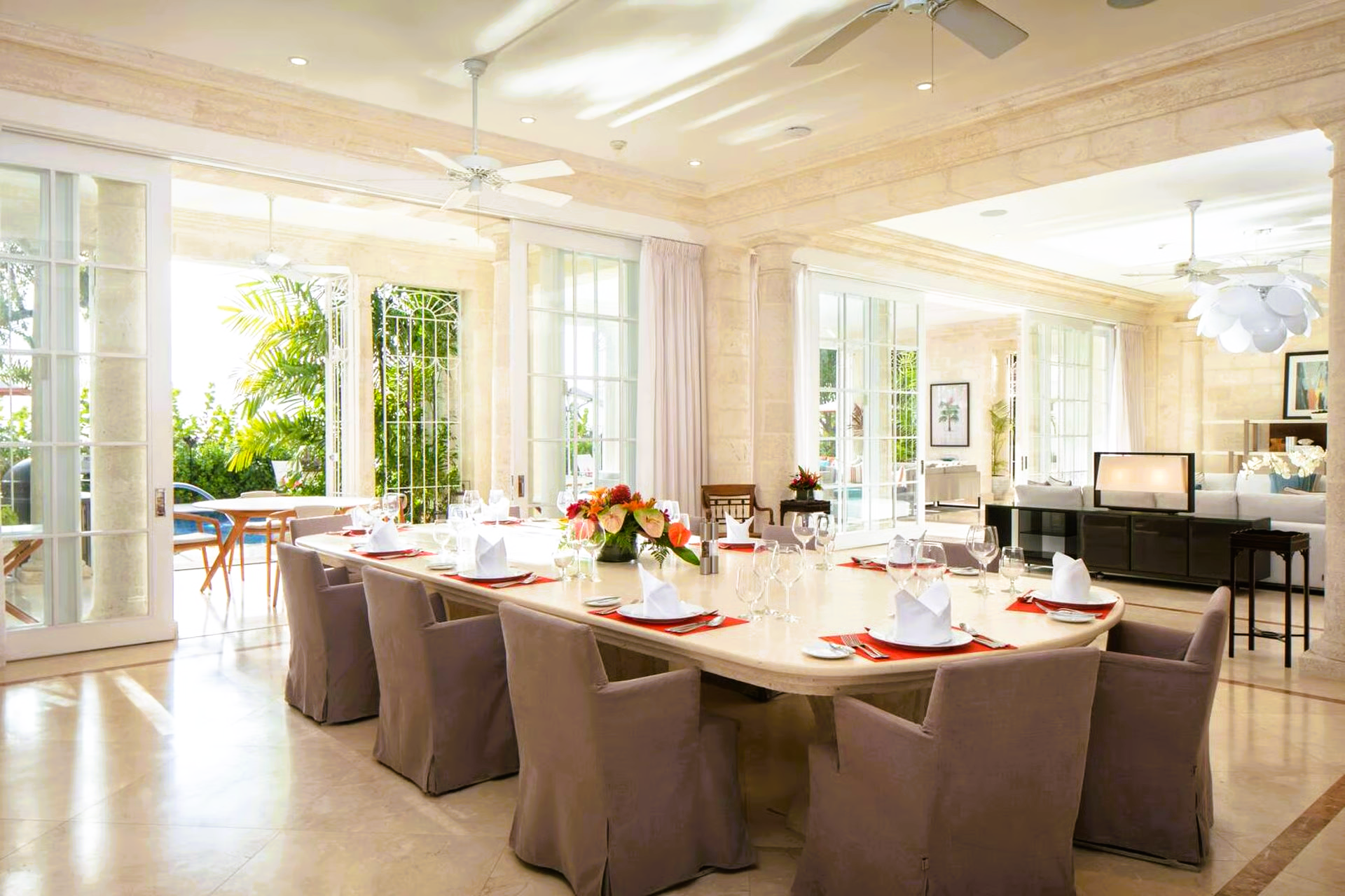 Elegant dining room with long table set for guests, open doors to patio, light colors.