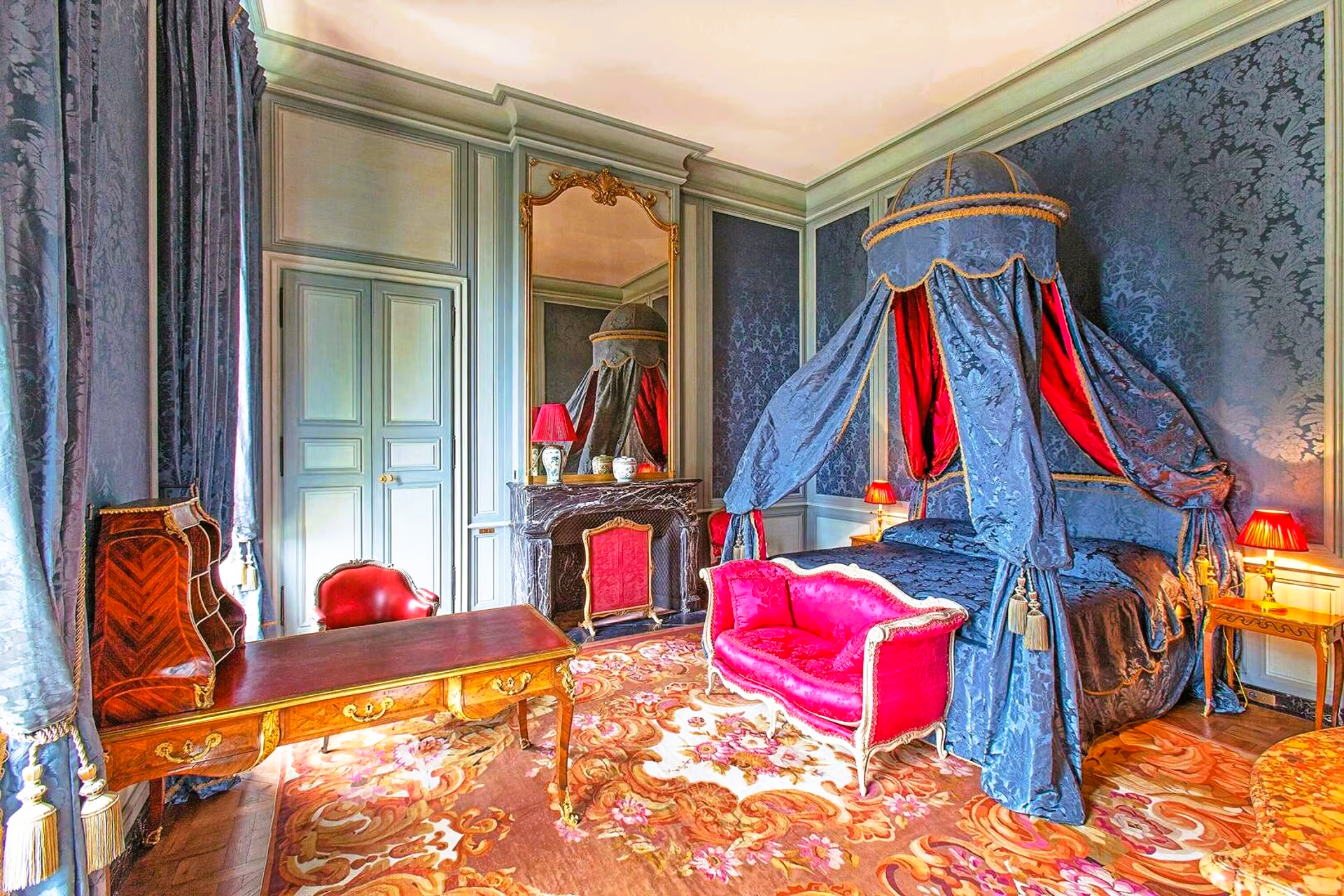 A bedroom with a canopy bed and a red couch.