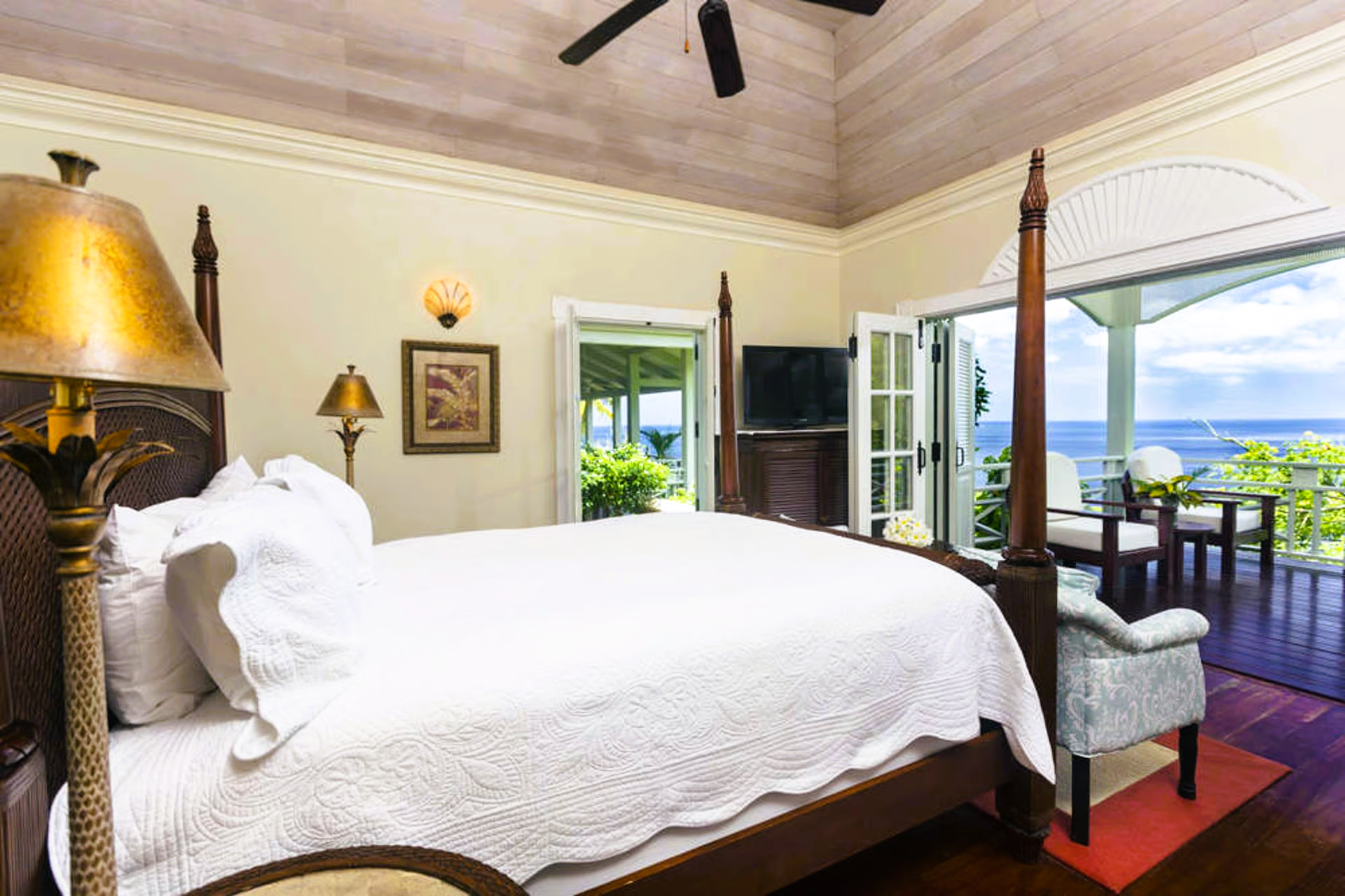 Bedroom with a large bed, opening onto a balcony with a sea view.
