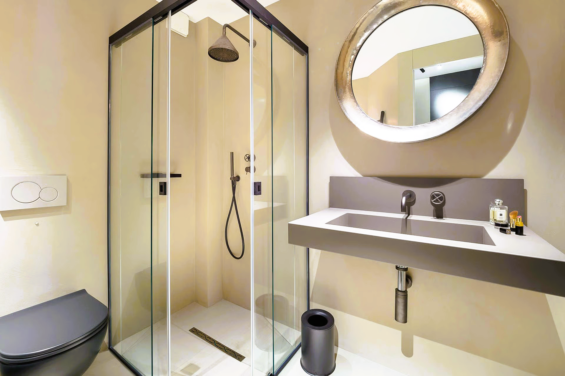 Modern bathroom with glass shower, floating sink, and round mirror.