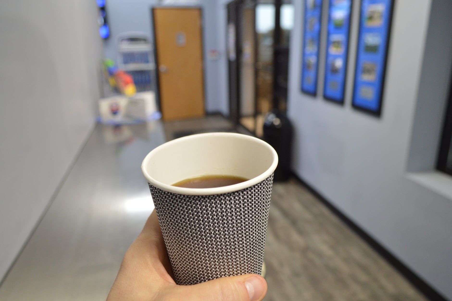Cup full of coffee held by hand in front of hallway | Full Throttle Automotive LLC