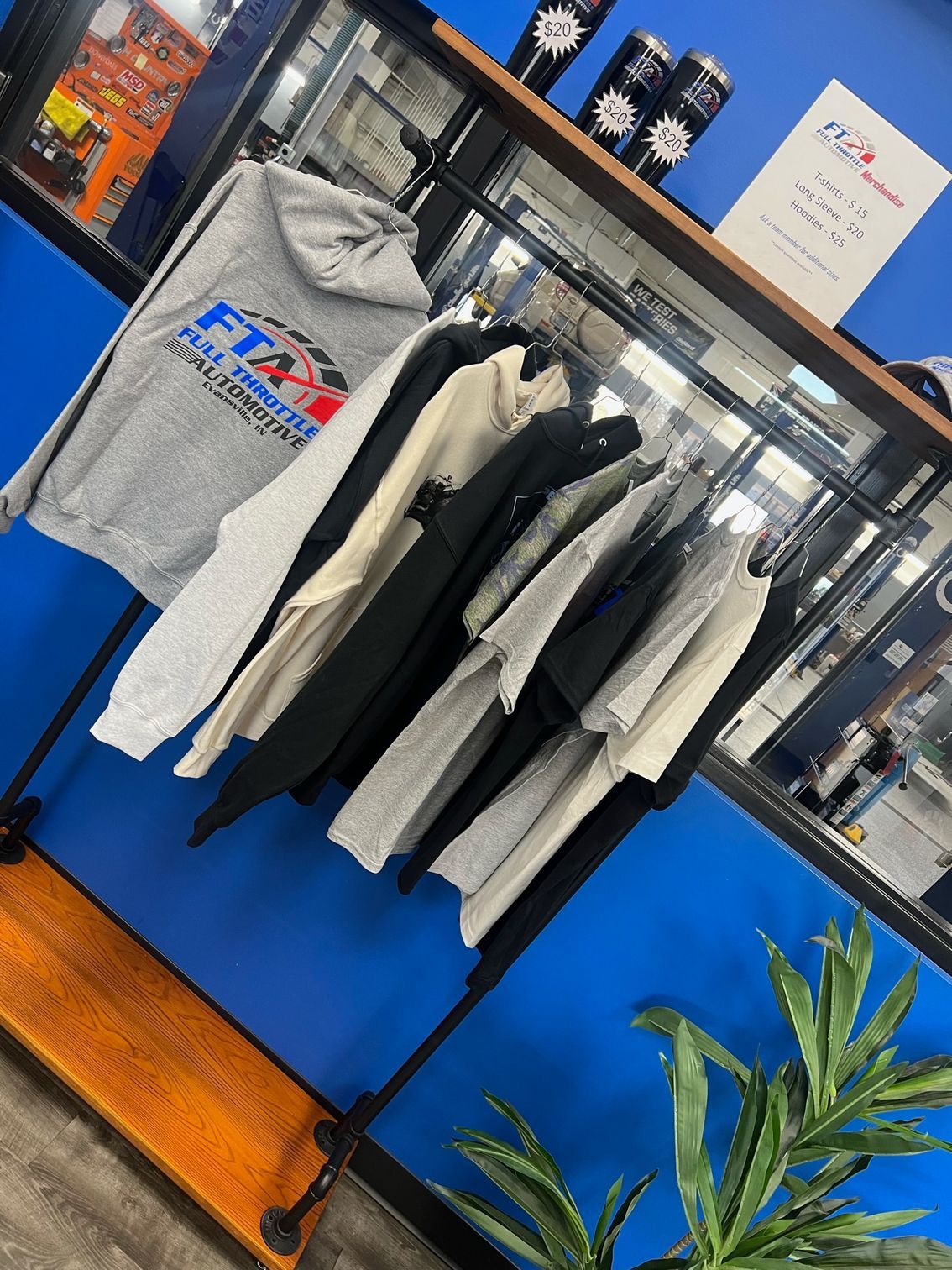 Our clothing merchandise hung up and tumblers on top of the shelf | Full Throttle Automotive LLC