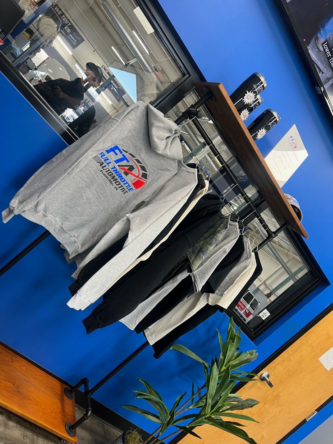 Our clothing merchandise hung up and tumblers on top of the shelf | Full Throttle Automotive LLC