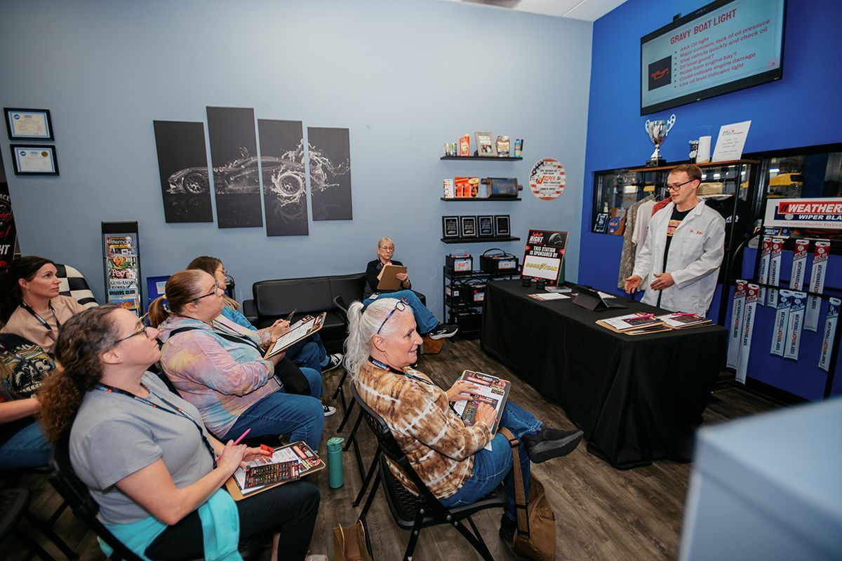 Group of women sitting and listening as a technician explains warning lights in vehicles | Full Throttle Automotive LLC