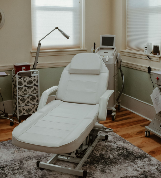Modern white treatment chair in a bright spa room with equipment and hardwood floors