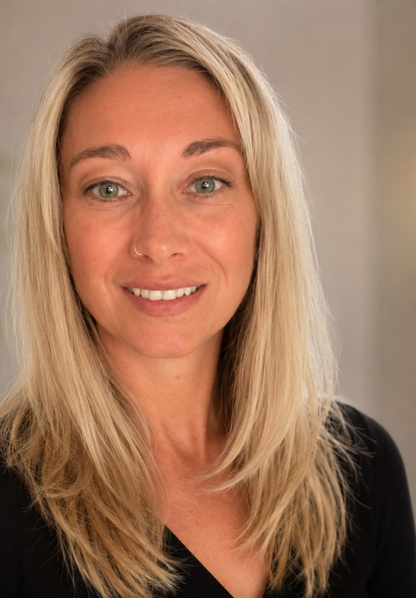 Portrait of a smiling blonde woman in a black top against a neutral background