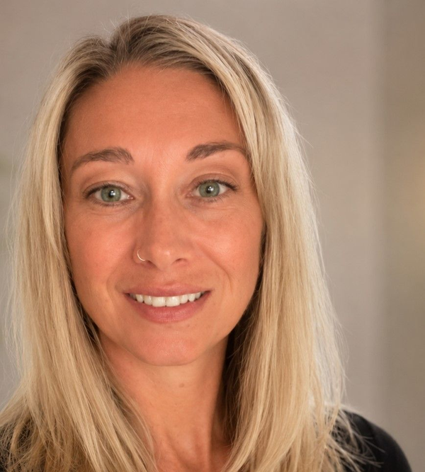 Portrait of a smiling blonde woman in a black top against a neutral background