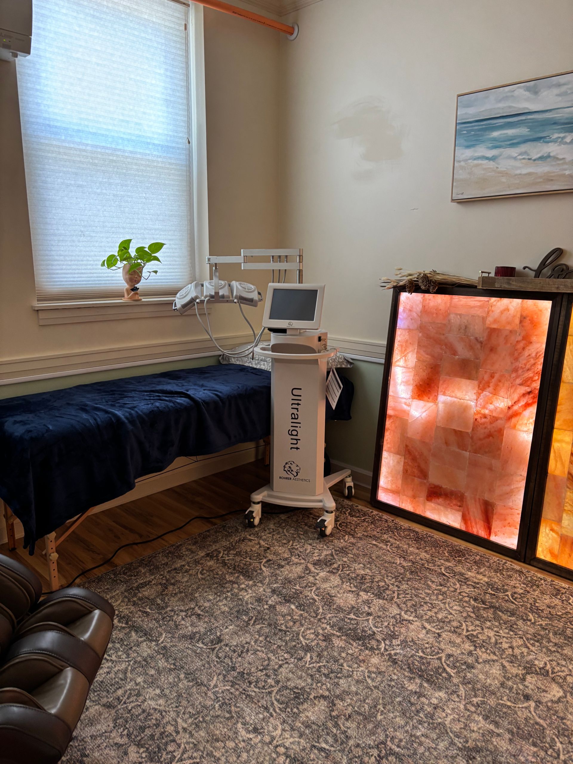 A treatment room with bed, medical equipment, and a Himalayan salt wall.