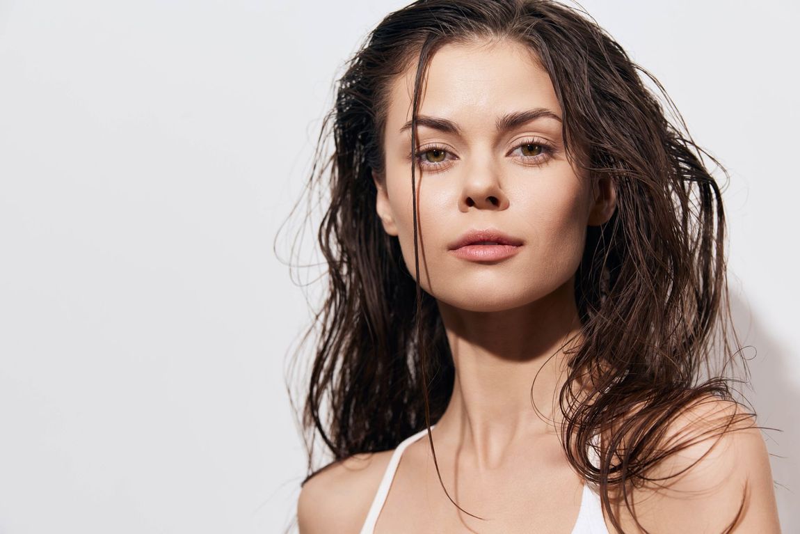 Portrait of a woman with wet dark hair against a light background