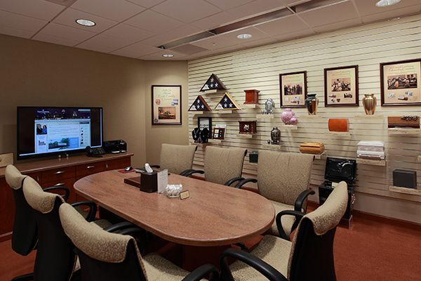 A meeting room with a table, chairs, TV, and items on display, possibly related to memorials.