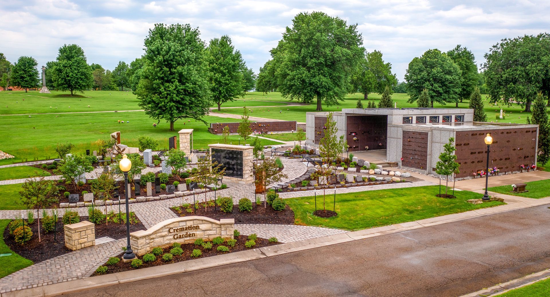 Aerial view of a memorial garden with pathways, landscaping, and a gazebo on a grassy landscape.