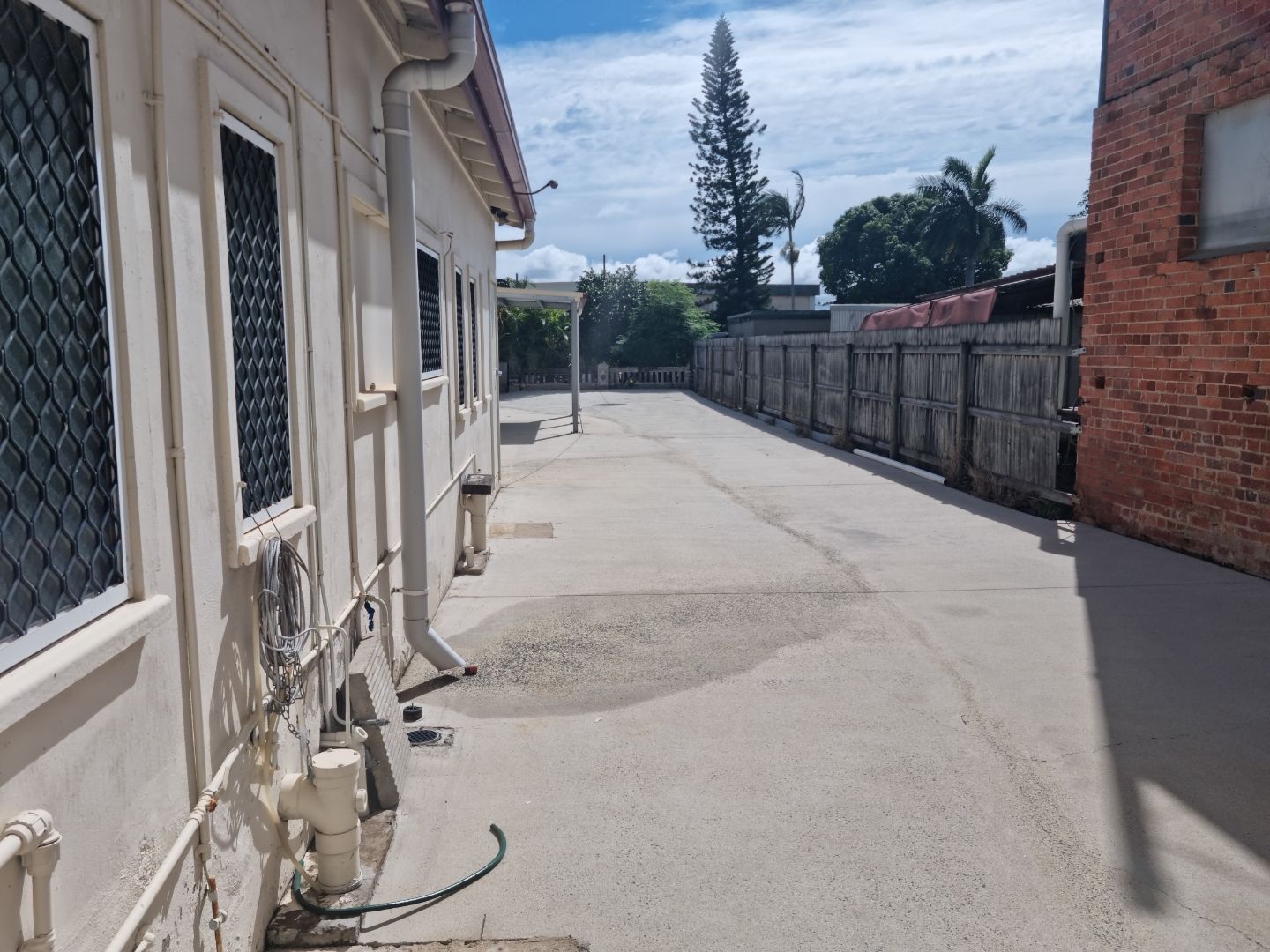 A Woman is Using a Pressure Washer to Clean a Driveway — Blast H2O In Proserpine, QLD
