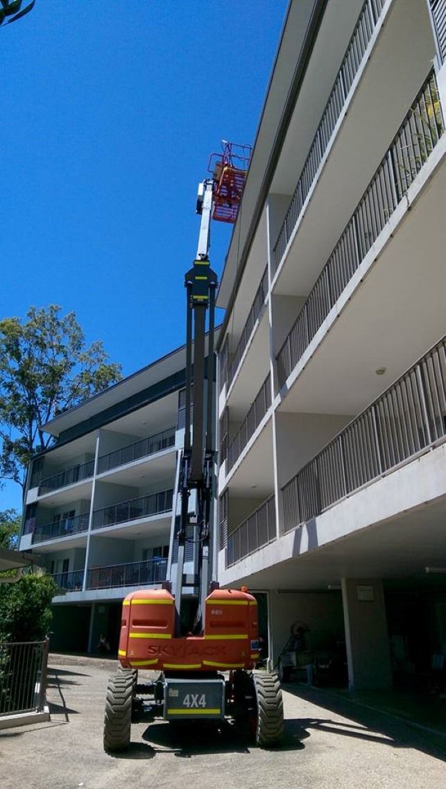 A Crane is Sitting in Front of a Large Building — Blast H2O In Proserpine, QLD