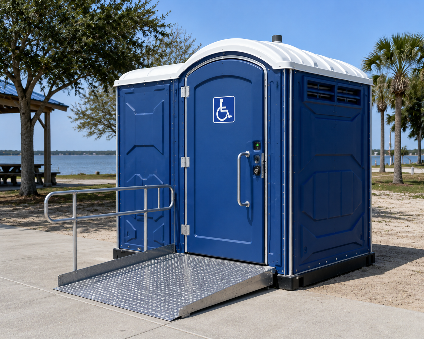Blue accessible portable toilet with ramp by the beach, marked with a wheelchair symbol