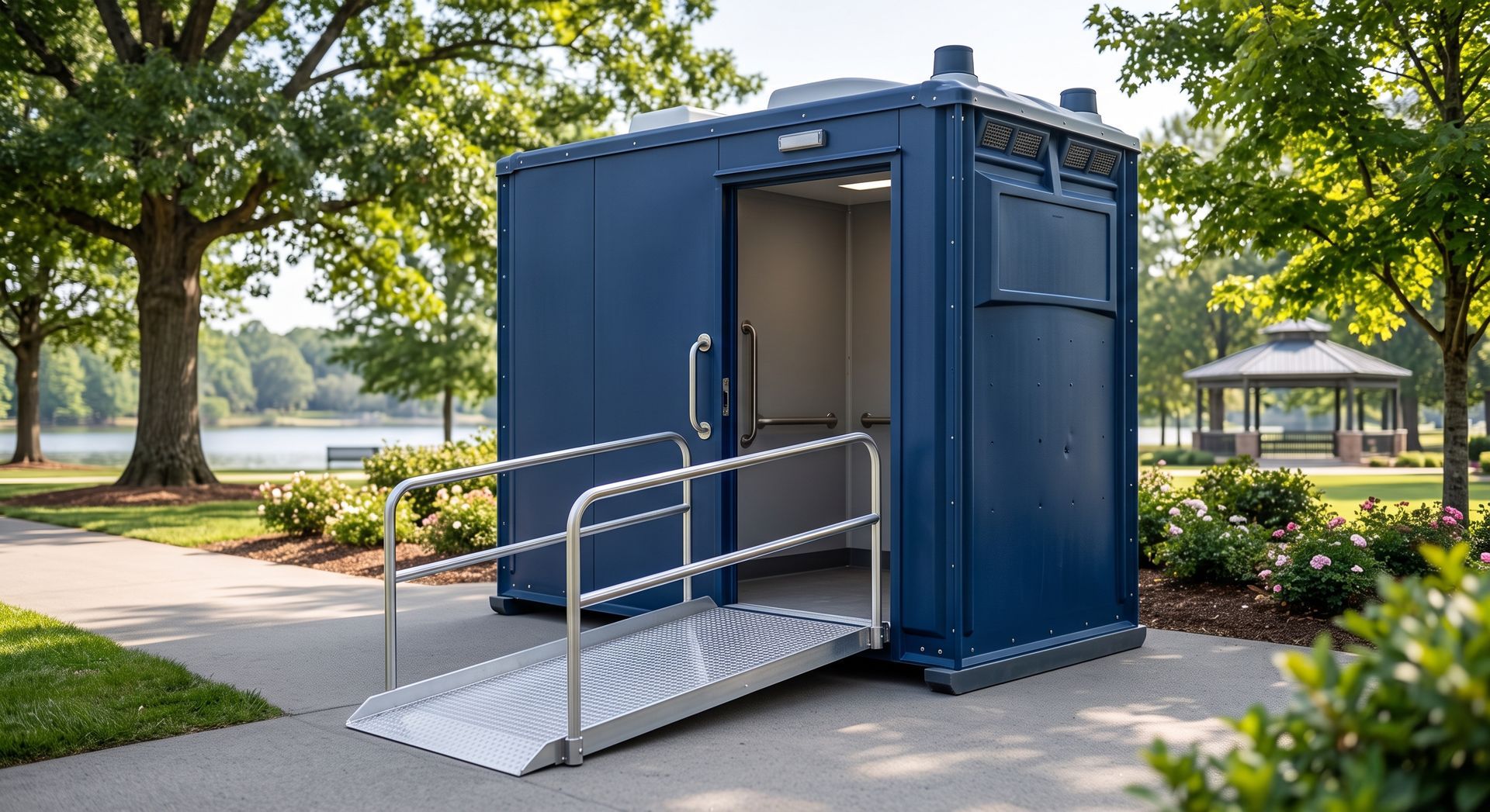 Blue accessible portable toilet with wheelchair ramp and handrails outdoors